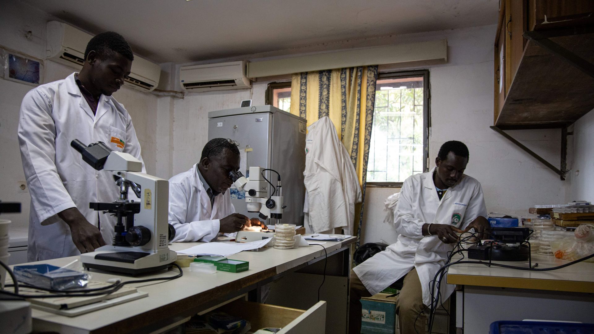 Photo of 3 entomologists studying malaria in a lab in Burkina