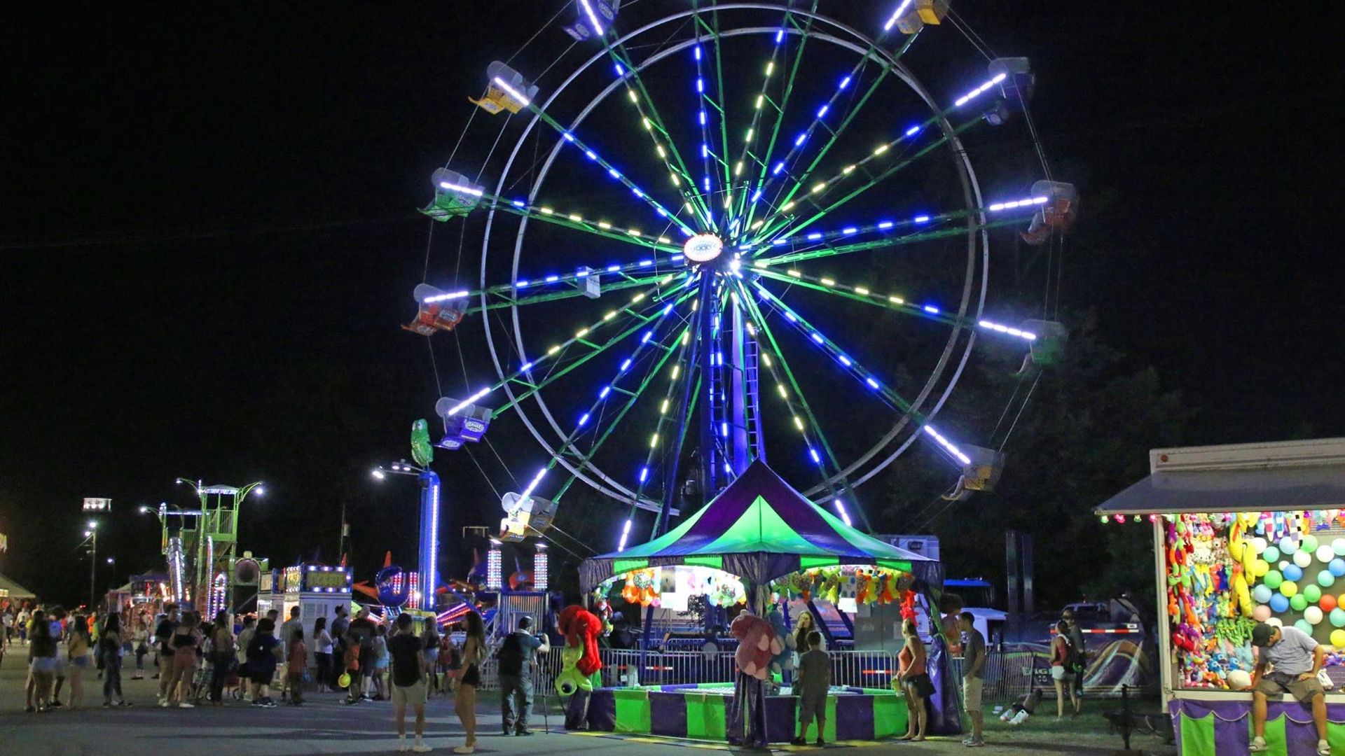 A Ferris wheel lit up at night on the fair midway