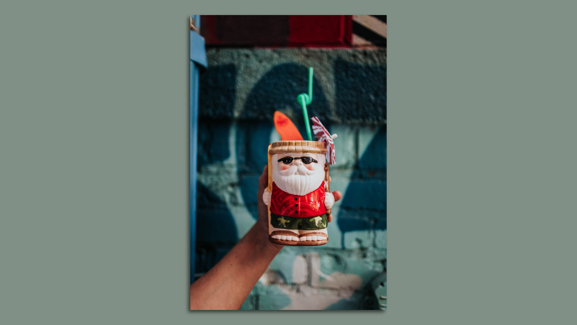 A mug in the shape of santa in summer attire with a straw sticking out.