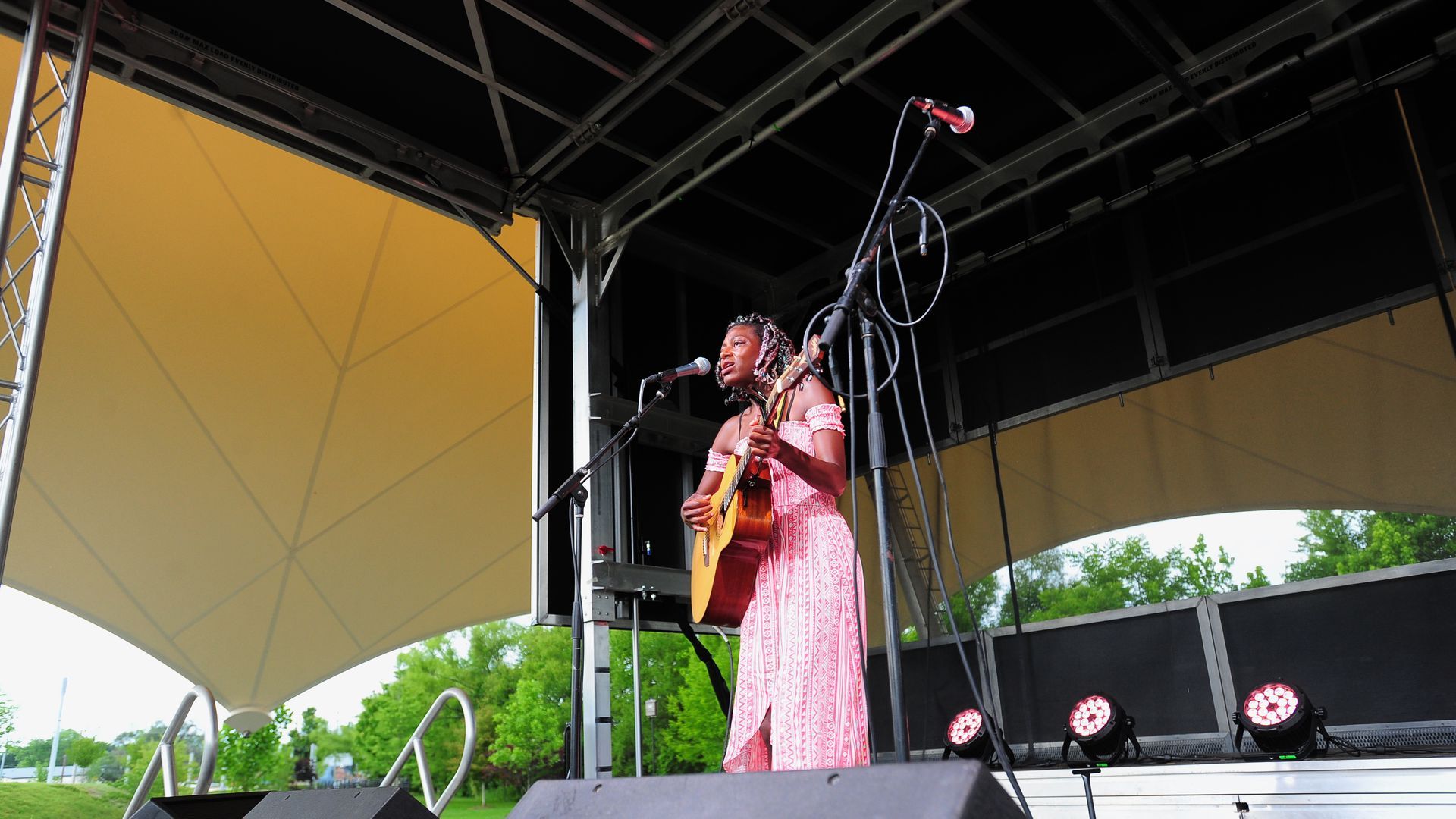 A woman stands on stage playing guitar and singing into a microphone