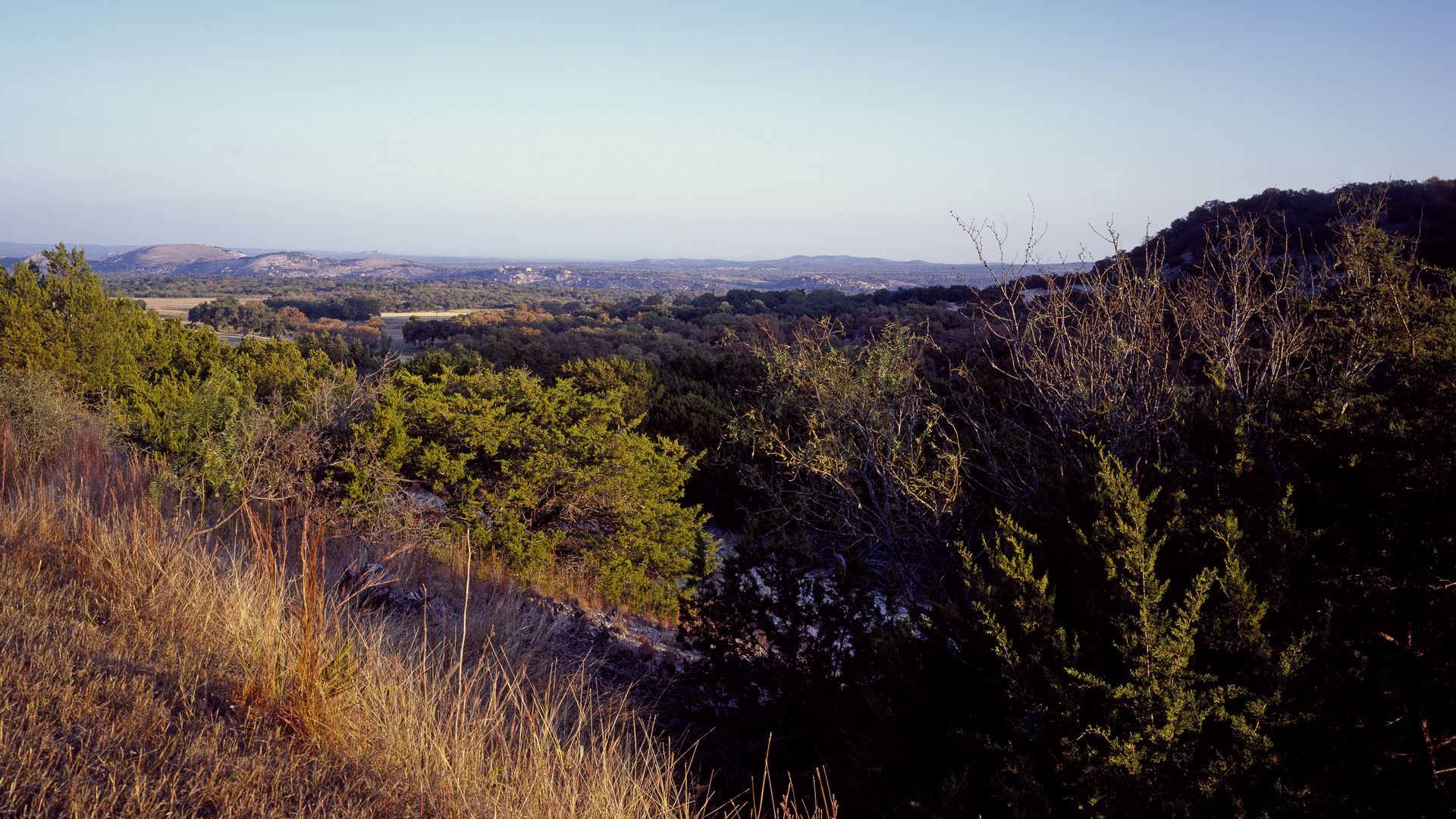 A beautiful view of Enchanted Rock against a pale blue sky.