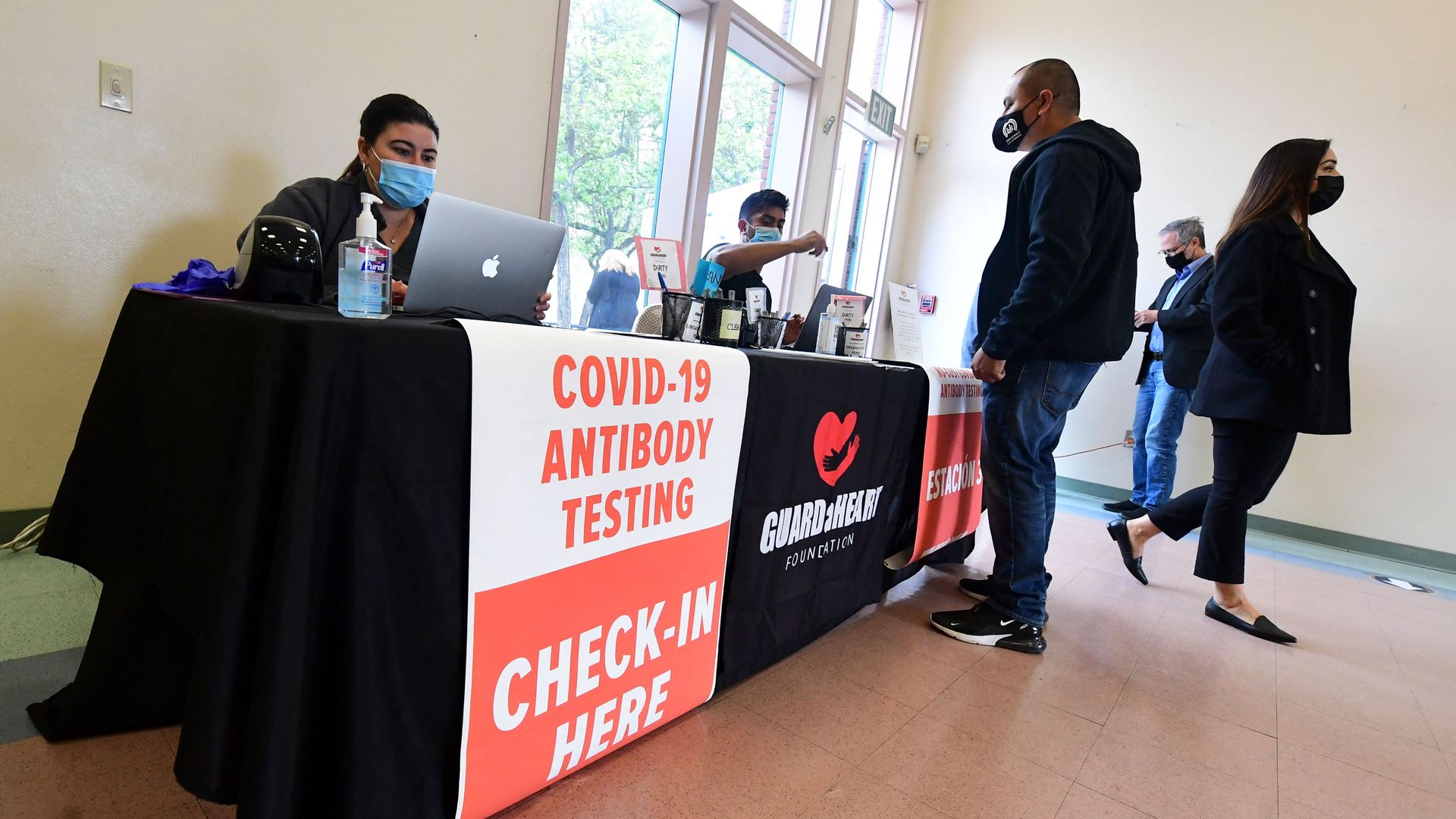 Photo of a booth set up with a sign that says "Covid-19 antibody testing, check in here"