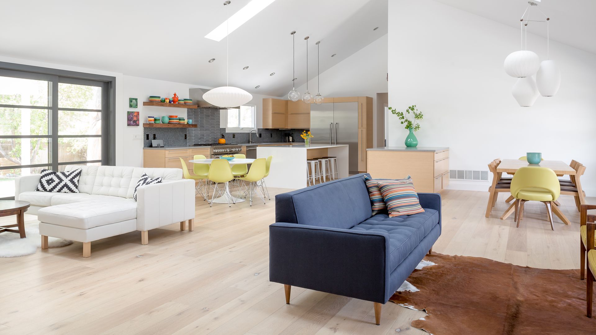 Interior of a home with white walls, wooden flooring, vertical windows and an open floor plan