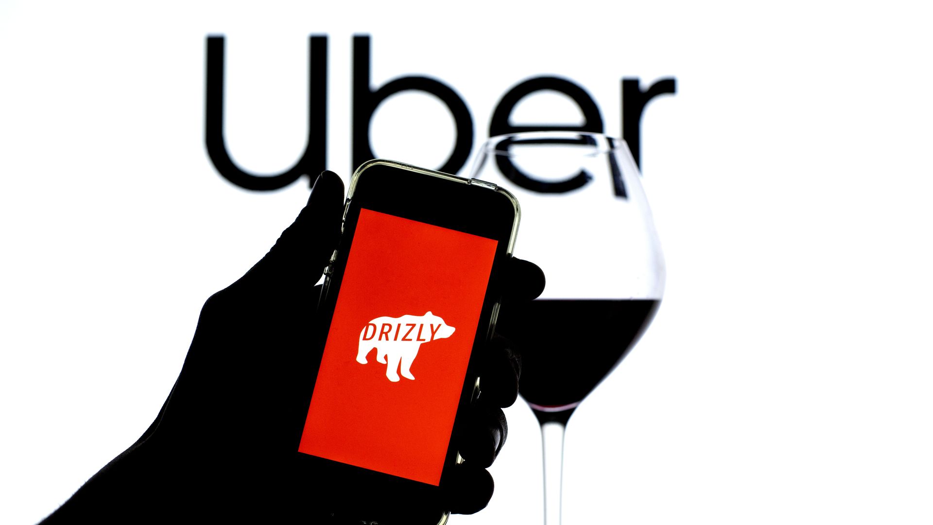 Uber logo behind Drizly app, with a glass of wine.