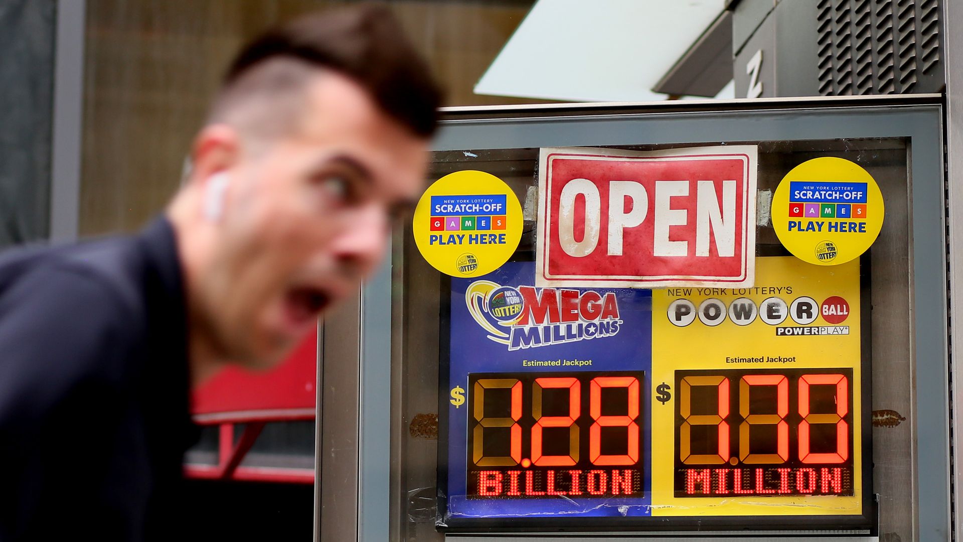 Man in front of lottery sign showing $1.28 billion Mega Millions jackpot