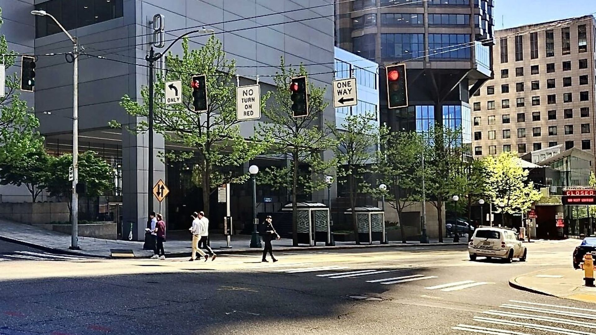 A view of an intersection with "No Right on Red" signs and people crossing in Seattle.