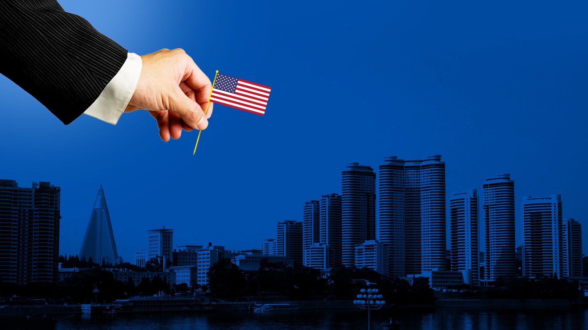 A hand places an American flag on a cityscape.