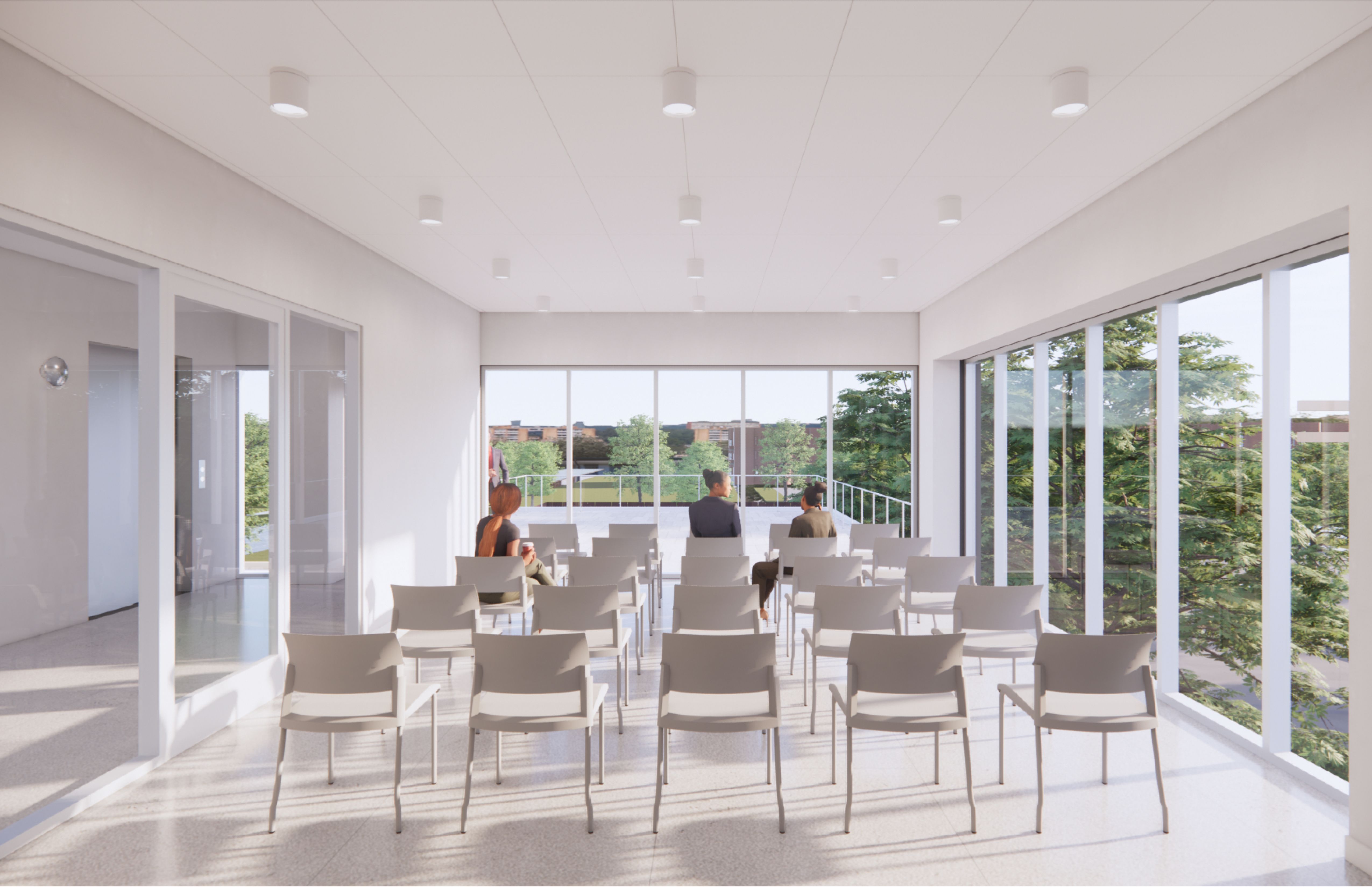 Inside a bright room surrounded by windows with trees and white chairs set up in rows with people sitting in them.