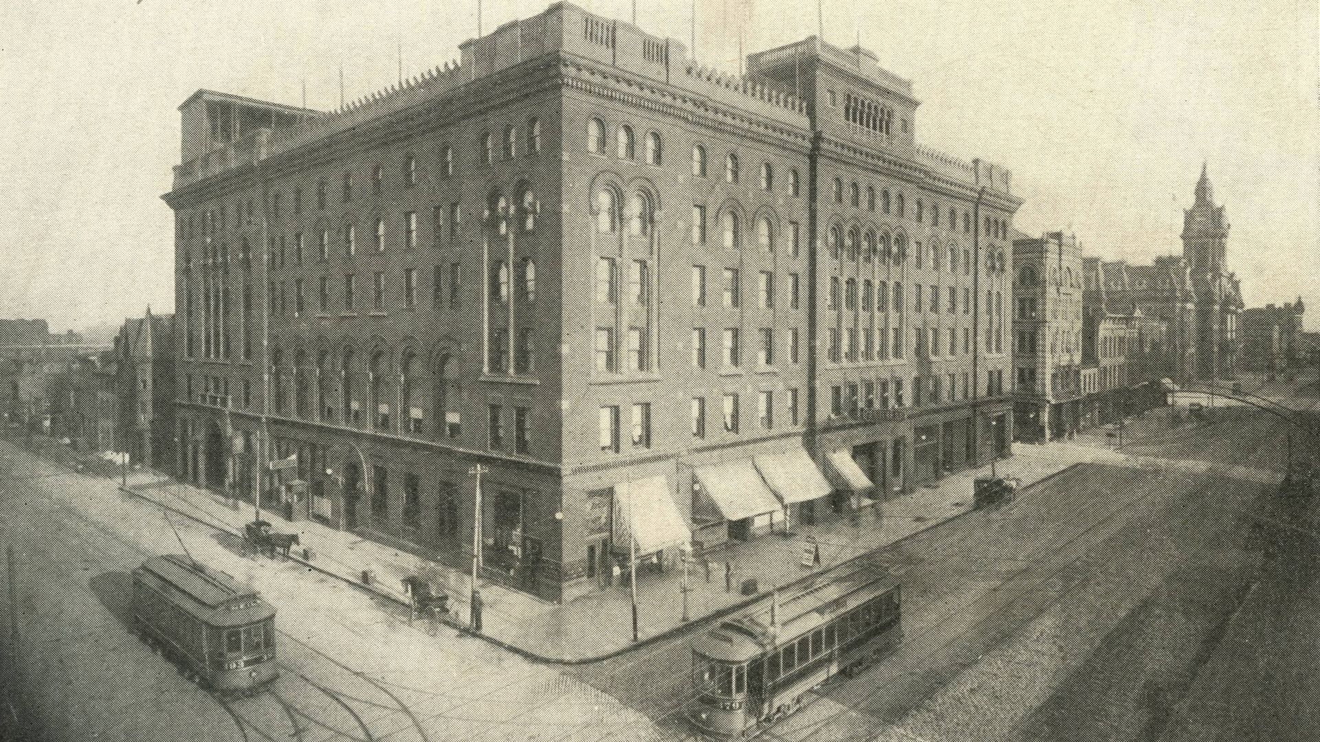 Black-and-white historical street scene with the Great Southern Hotel (a large brick four-story building) on the left, ornate windows, trams on curved tracks in the foreground, overhead wires, and city skyline in the distance.