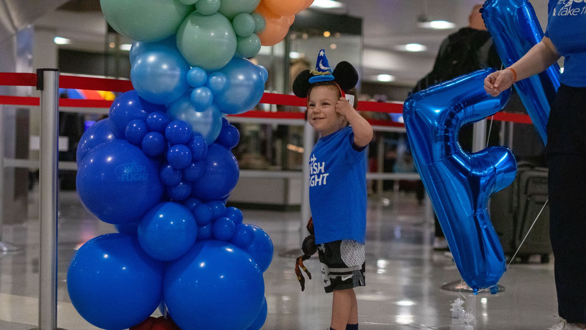 A young boy smiling and wearing Mickey Mouse ears.