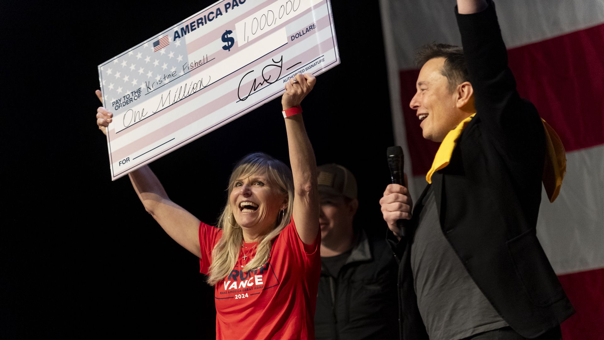Elon Musk awards Kristine Fishell with a $1 million check at a town hall.
