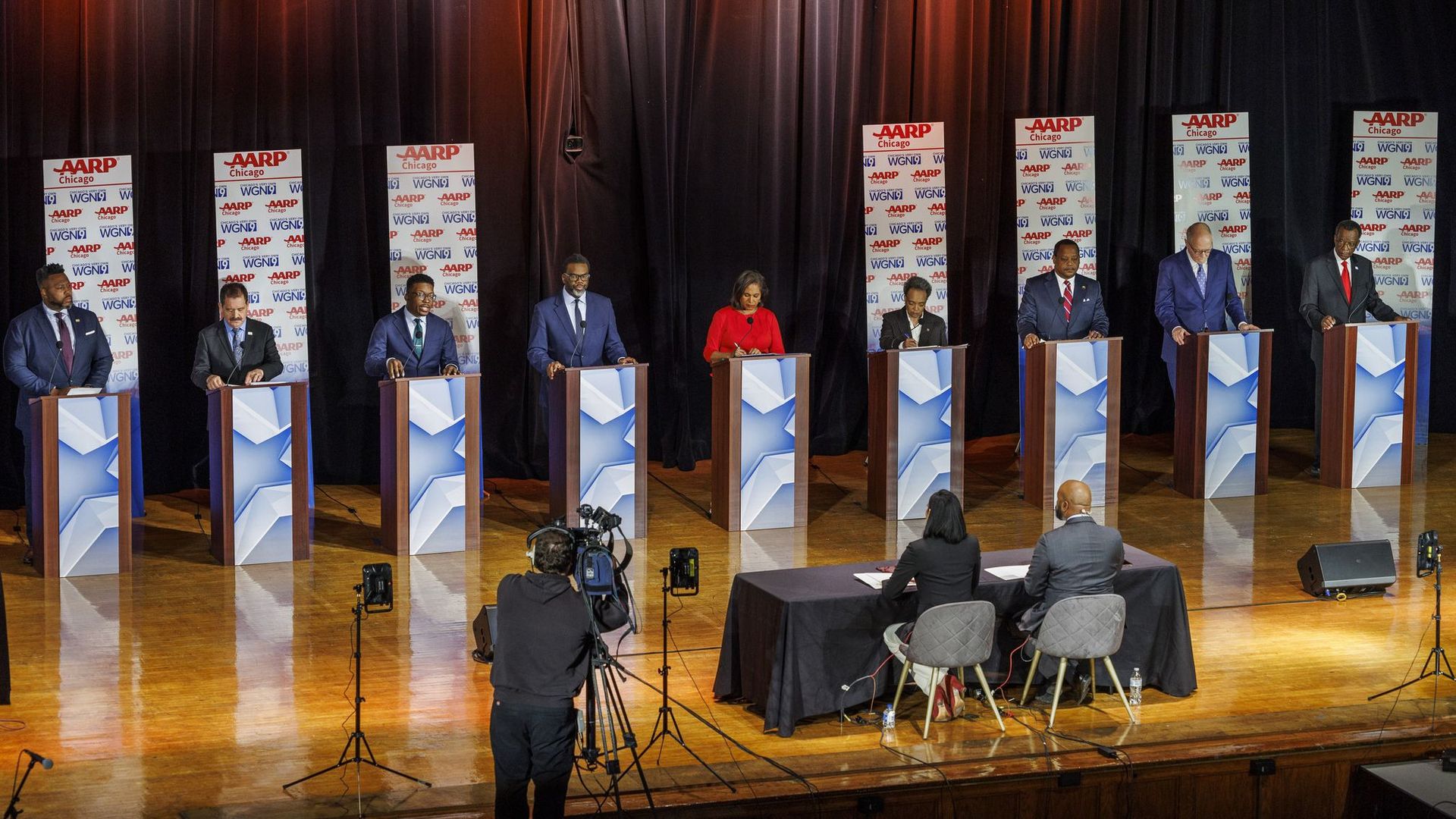 Photo of candidates behind podiums on stage at a debate. 