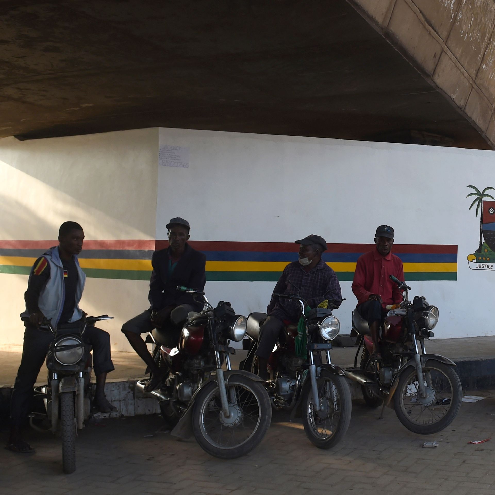motorbike taxis waiting for passengers in the shade under an overpass