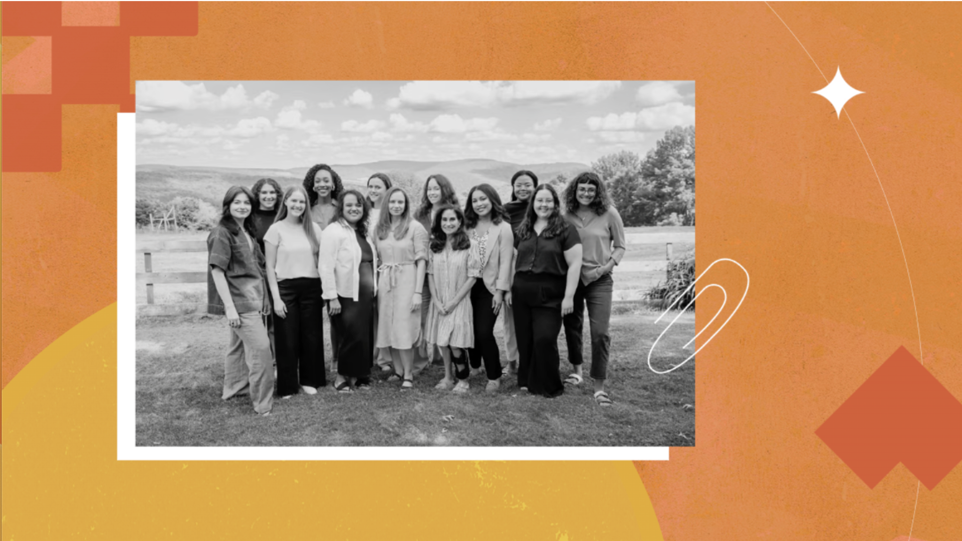 Black and white photo of fourteen women standing outdoors in a grassy area with hills and trees in the background under a partly cloudy sky.