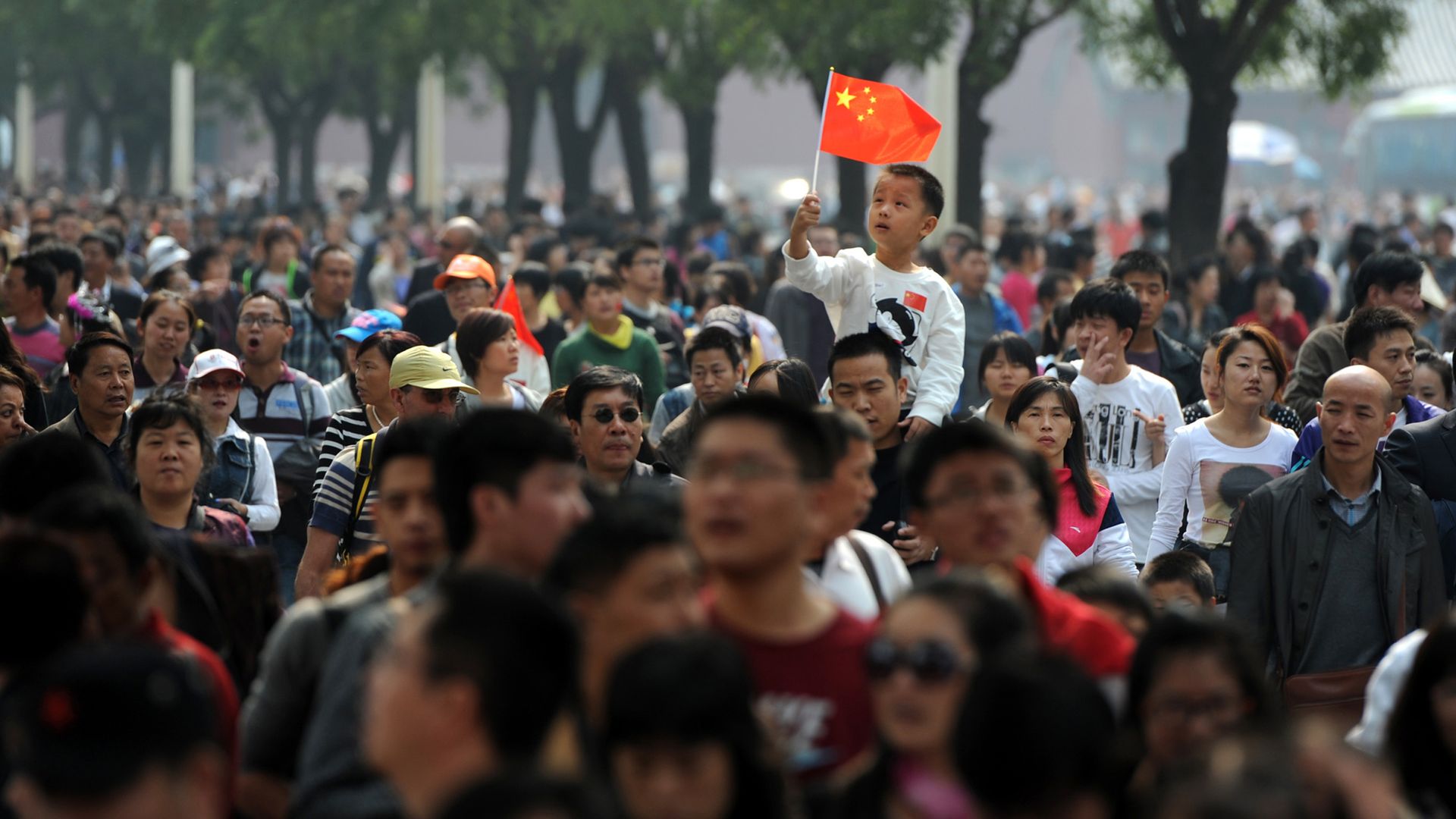 Photo of thousands of visitors making their way to the Forbidden City in Beijing for Golden Week with a cute boy on someone's shoulders waving a Chinese flag