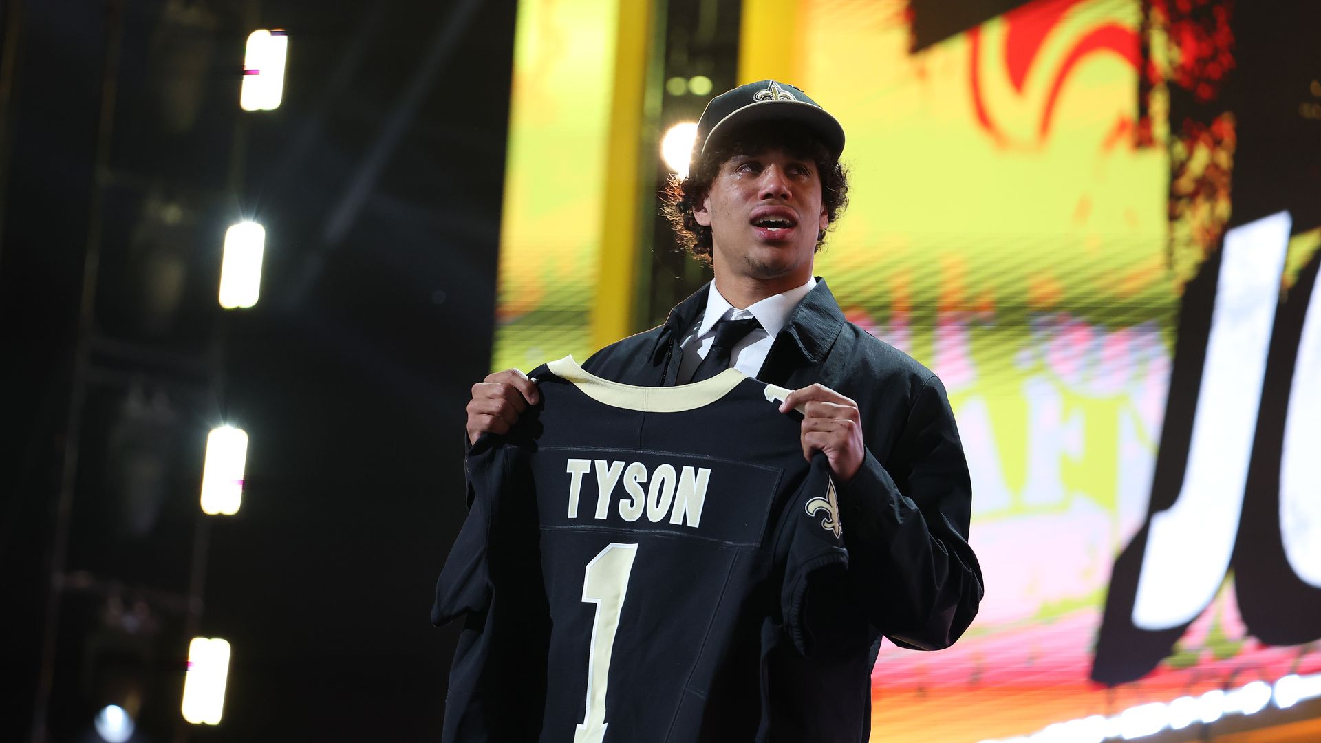 Arizona State football player Jordyn Tyson holds up a Saints jersey at the 2026 NFL draft.