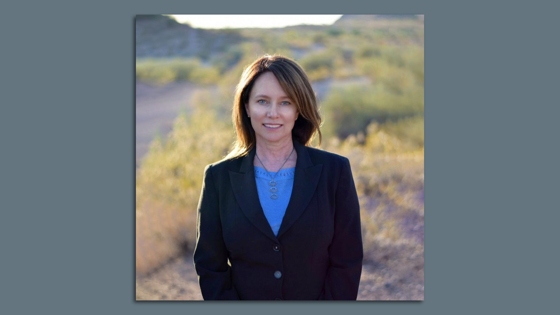 Brenda Burman poses in front of a desert landscape. 