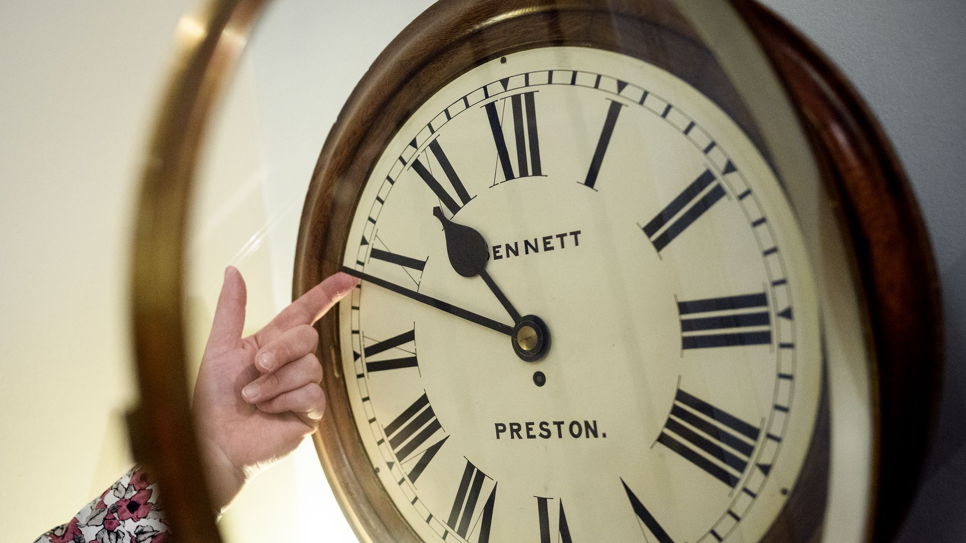 A person adjusts the hands on a clock. 