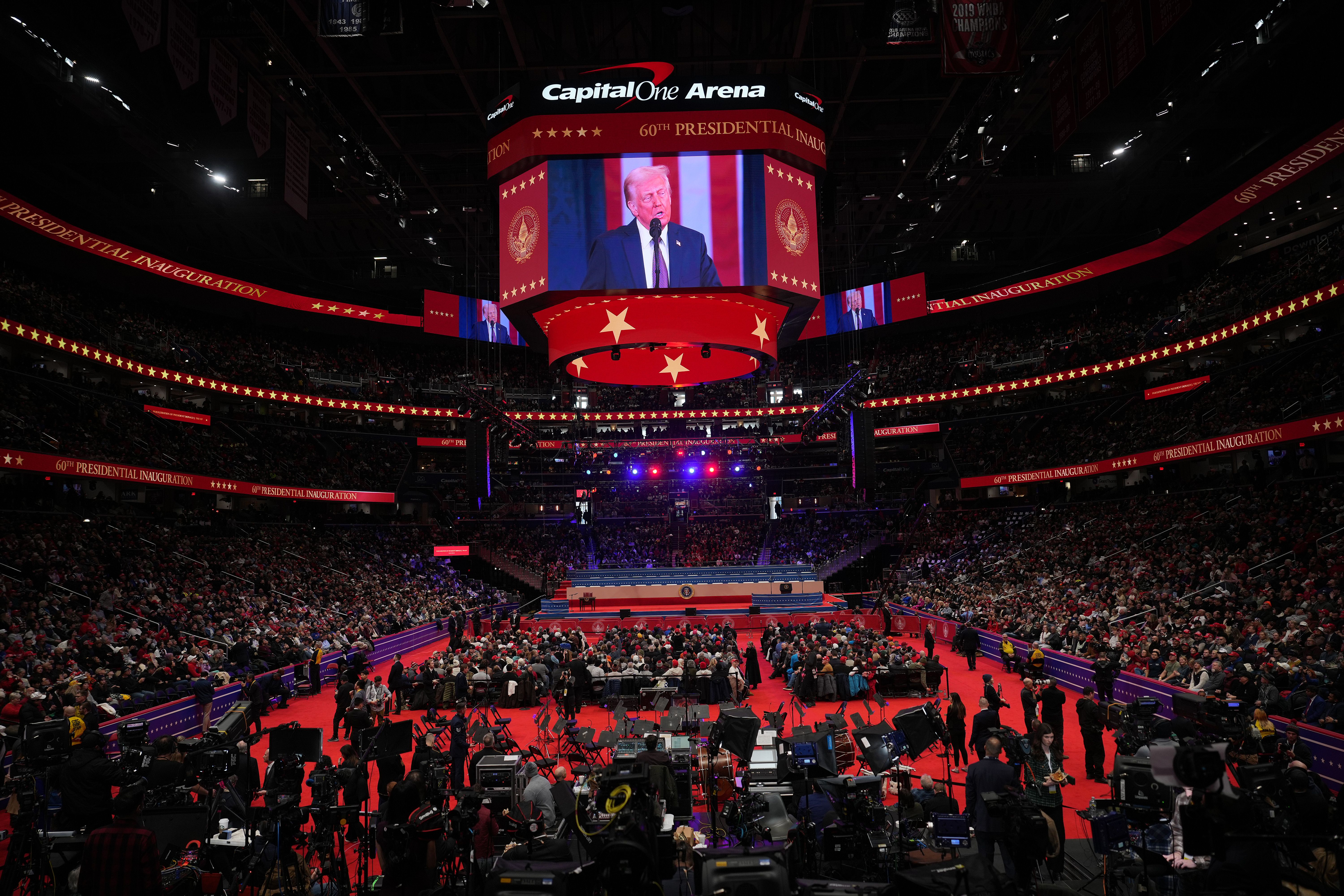 The mega tv screen inside Capital One Arena showing Donald Trump during his inauguration while thousands of spectators on the floor watch.