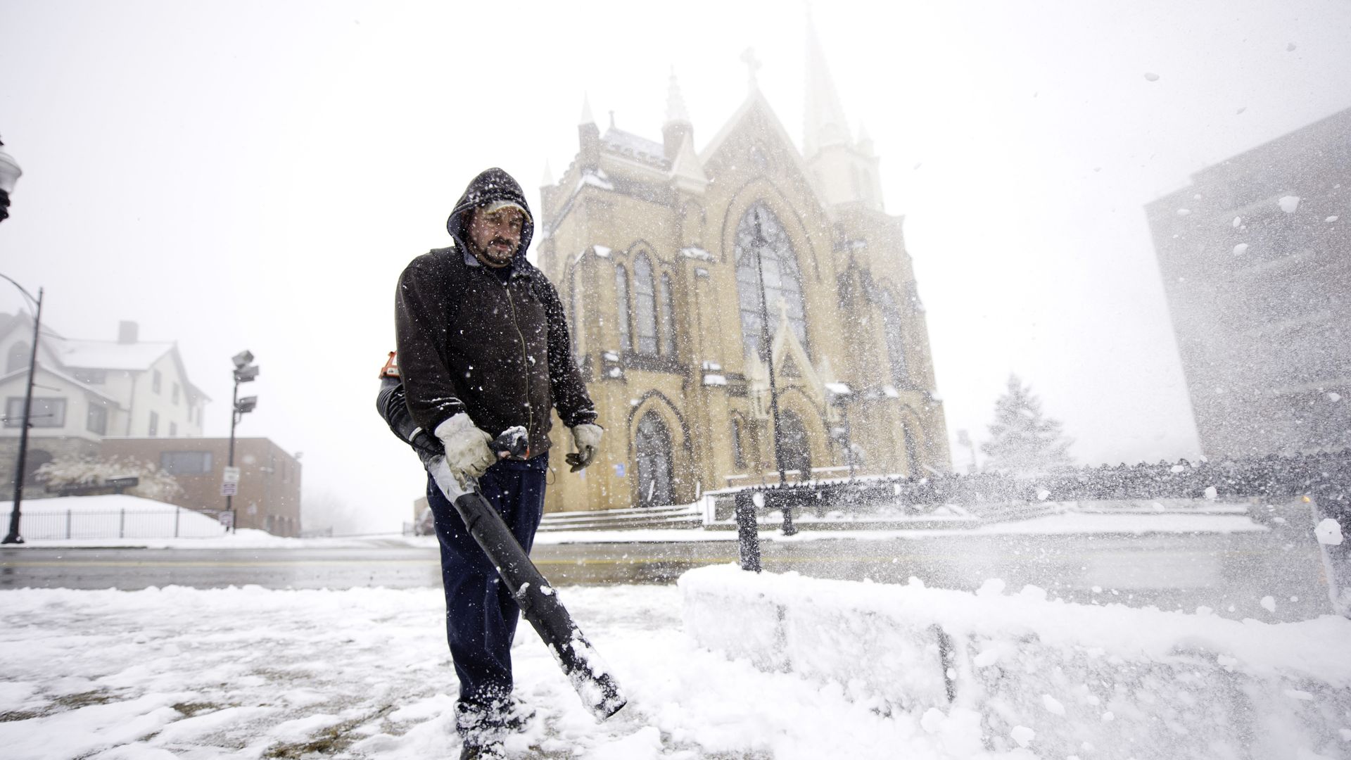 Mark Swigart, 41, uses a leaf blower to remove snow from the sidewalks along Grandview Avenue on November 26, 2013 in Pittsburgh, Pennsylvania. 