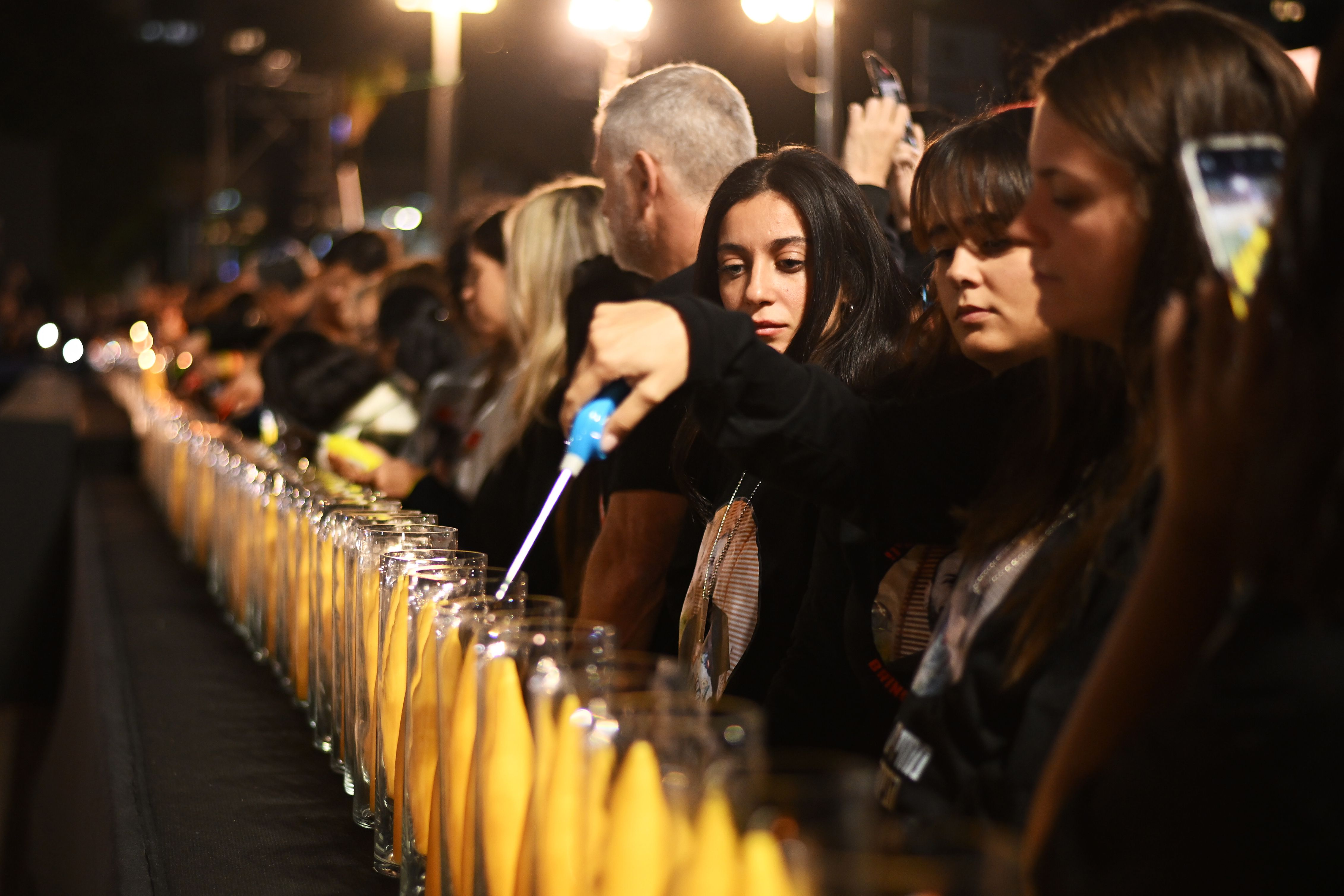 An image of people lighting a long line candles.