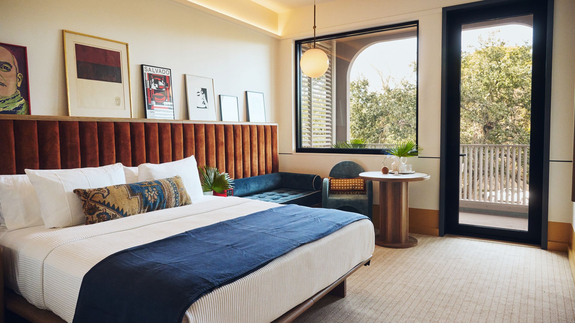 A modern-designed hotel room with art lined up along the wall with the bed.