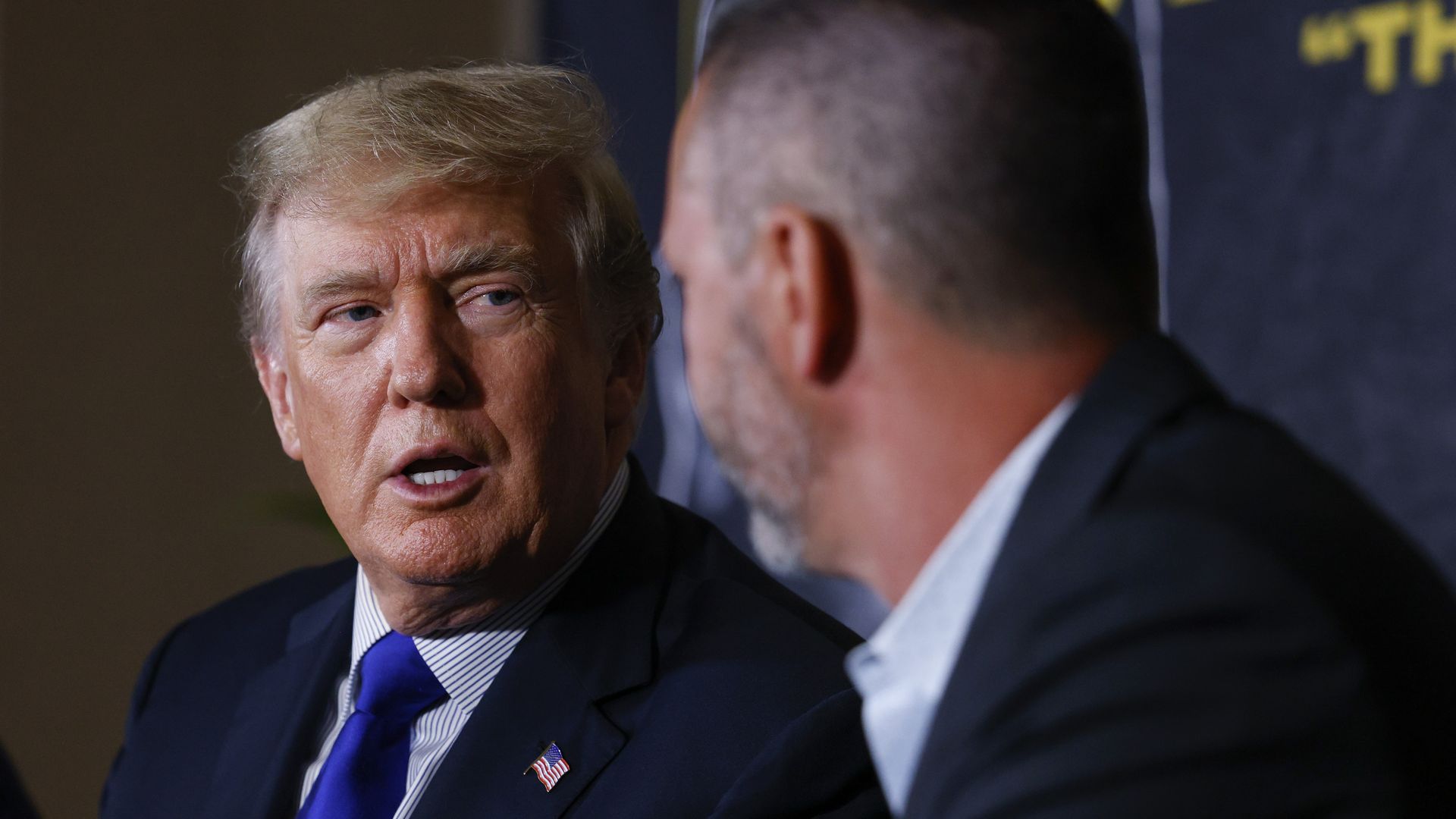 Photo of Donald Trump in a suit speaking with another person