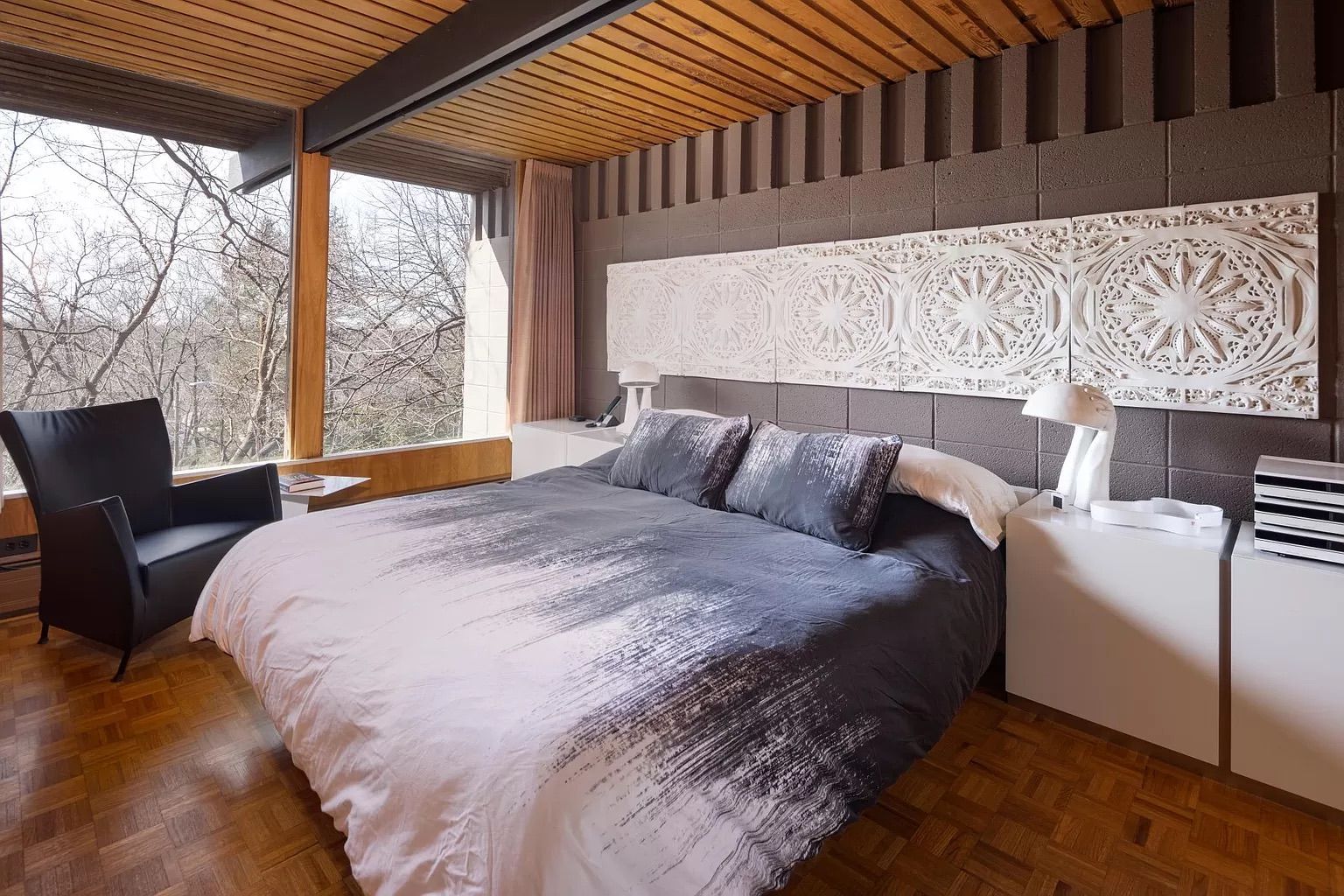 A bedroom with a gray bed and wall of windows.