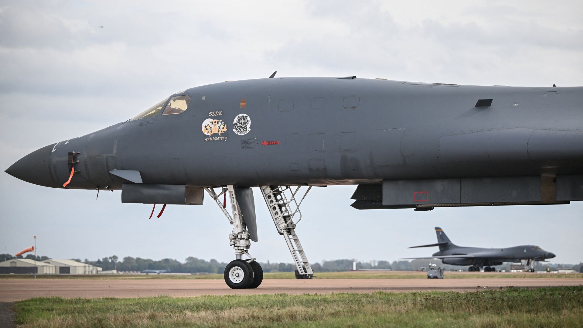 A B-1 bomber parking on the tarmac at a base, with another B-1 in the background.