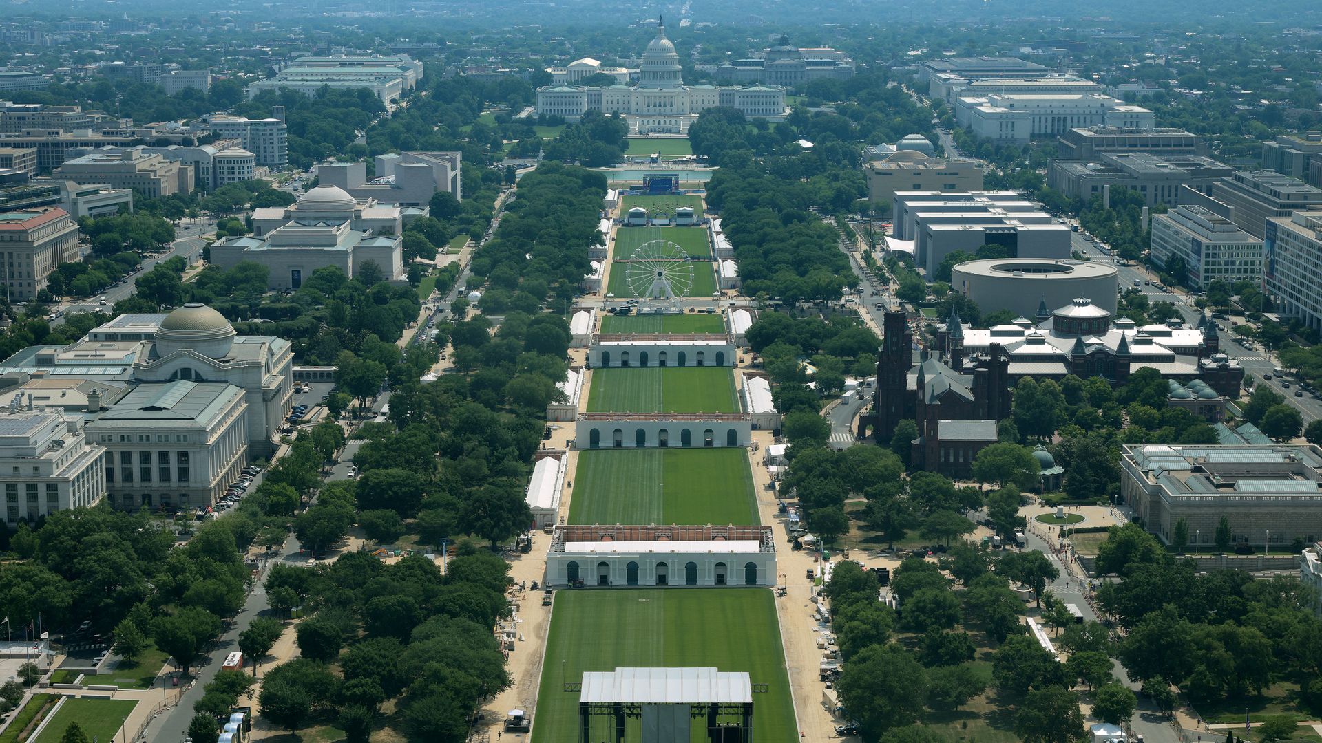 A birds-eye view of the National Mall as large tents are built along it and a Ferris wheel sits at the center.