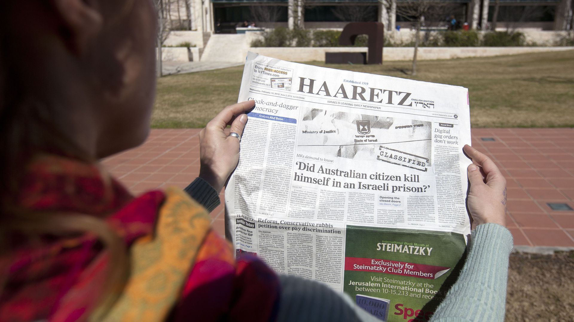 A woman shows the latest issue of the Haaretz daily newspaper whose cover page raises a question on the alleged suicide of an Australian prisoner with ties to Mossad on February 13, 2013 in Jerusalem. Twenty-four hours after the emergence of an explosive investigative report by Australia's ABC news,