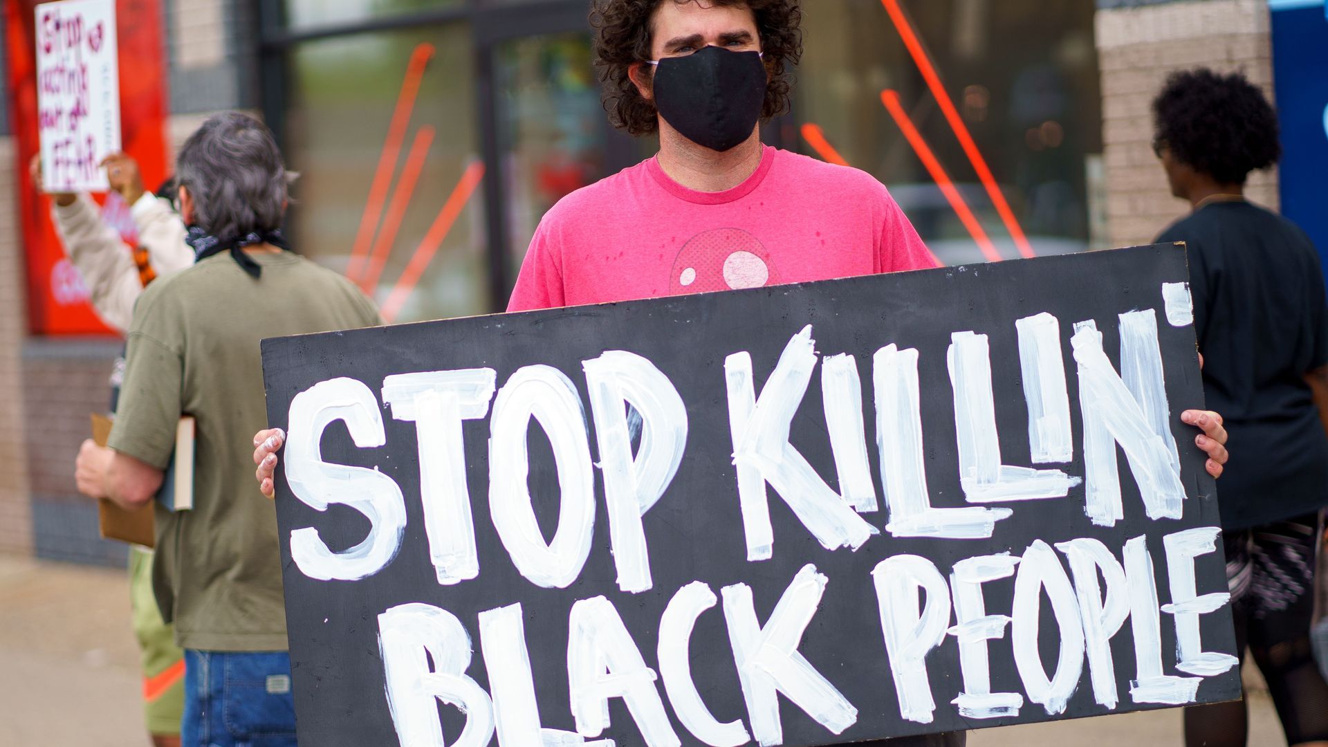 A man holds a 'Stop Killing Black People"" placard while protesting near the area where a Minneapolis Police Department officer allegedly killed George Floyd