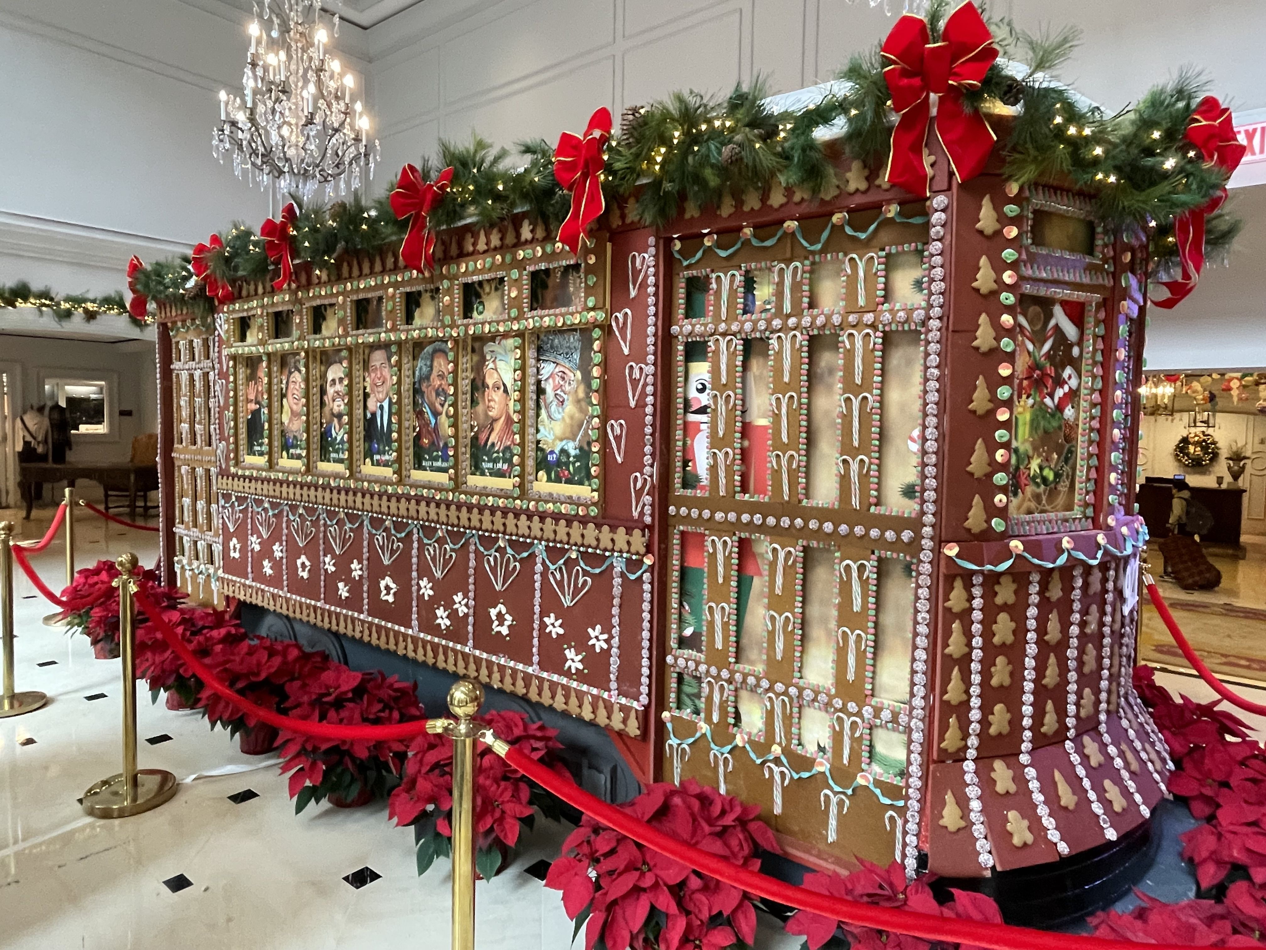 Image shows a gingerbread streetcar decorated with garland and bows.