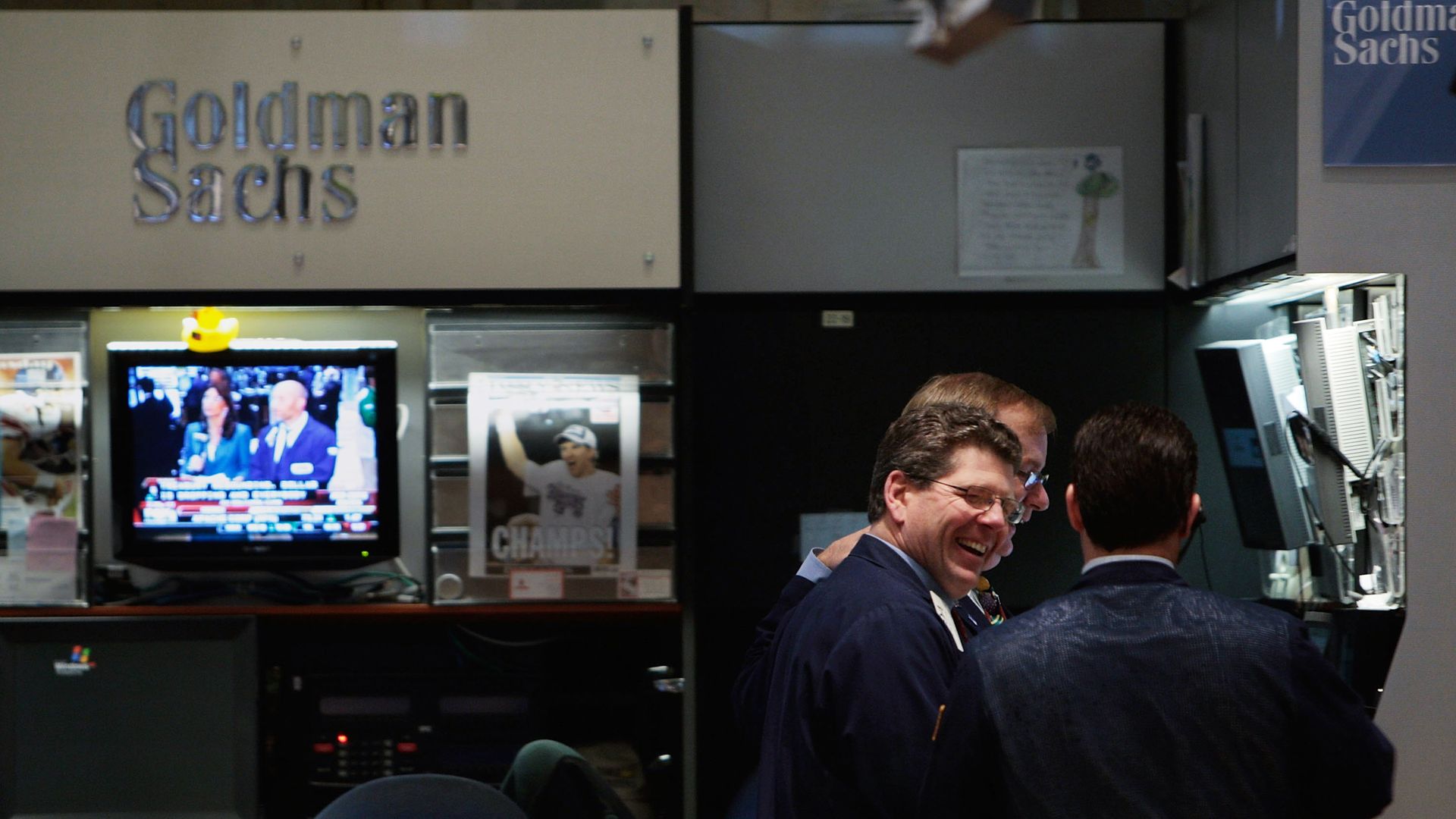 In this image, two men laugh in the Goldman Sachs booth at the New York Stock Exchange. 
