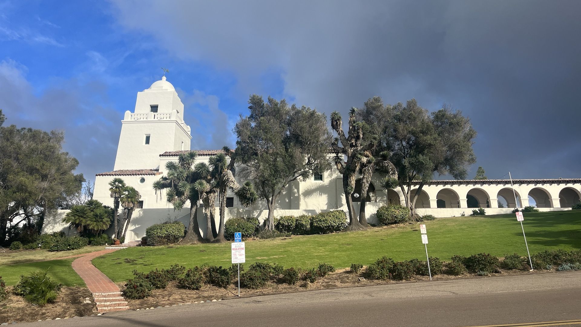 A white Spanish-style building on a grassy hill.