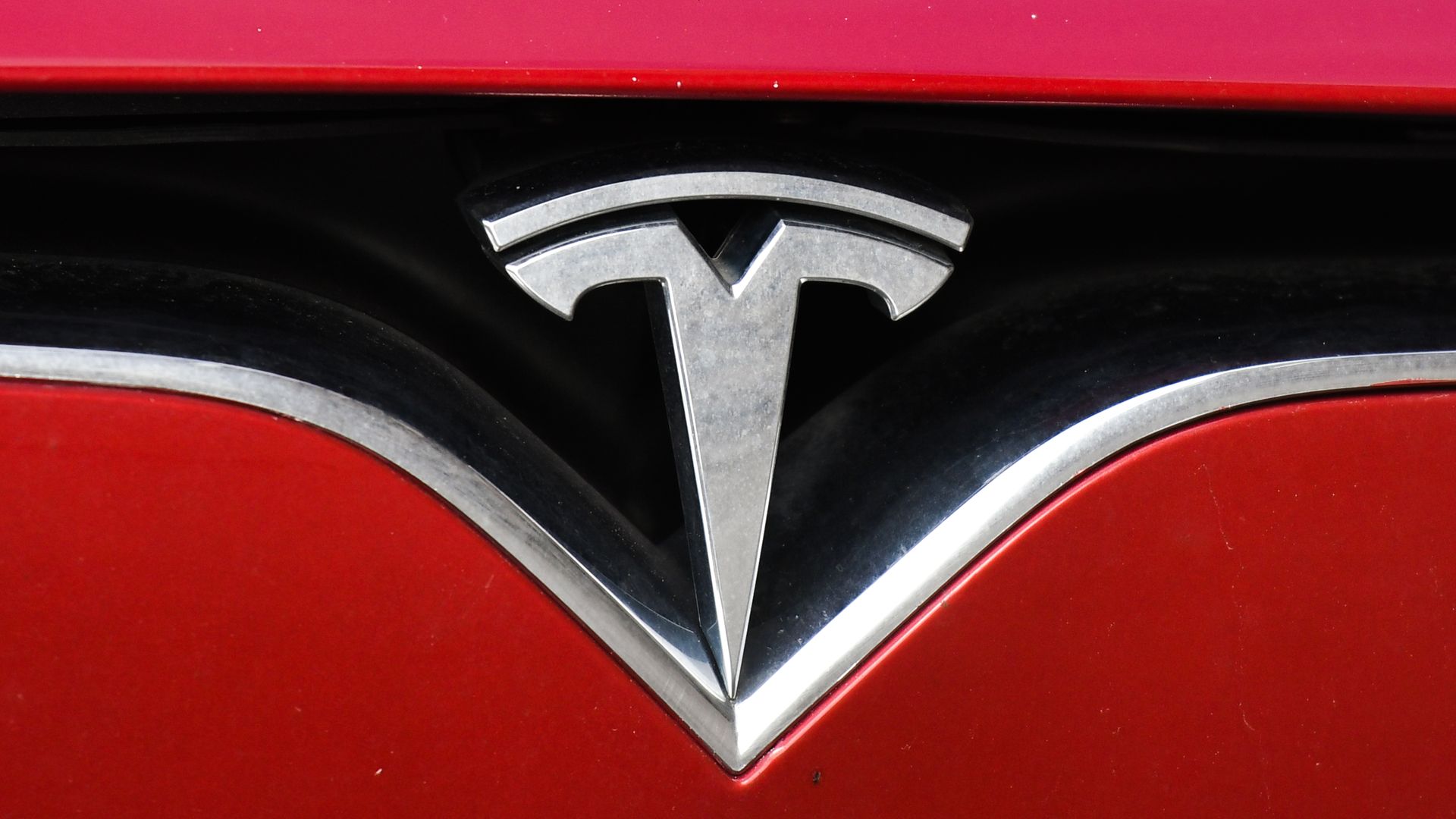 Close-up photo of Tesla logo on a red car. 