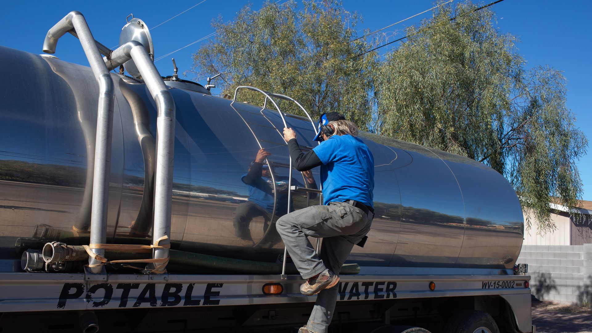 A man climbing a tank truck that says, "POTABLE WATER."