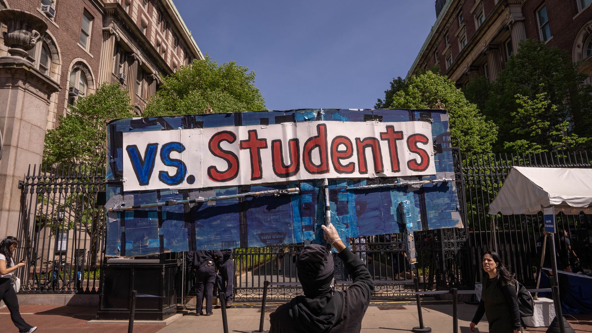 A person reads a sign that says "vs. Students" outside of Columbia University.