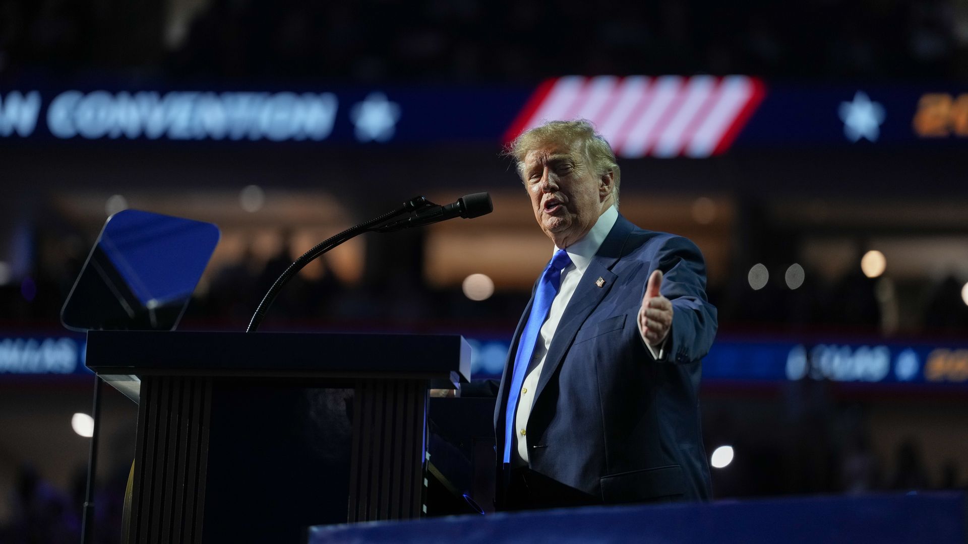 President Trump gestures to his left from a podium.