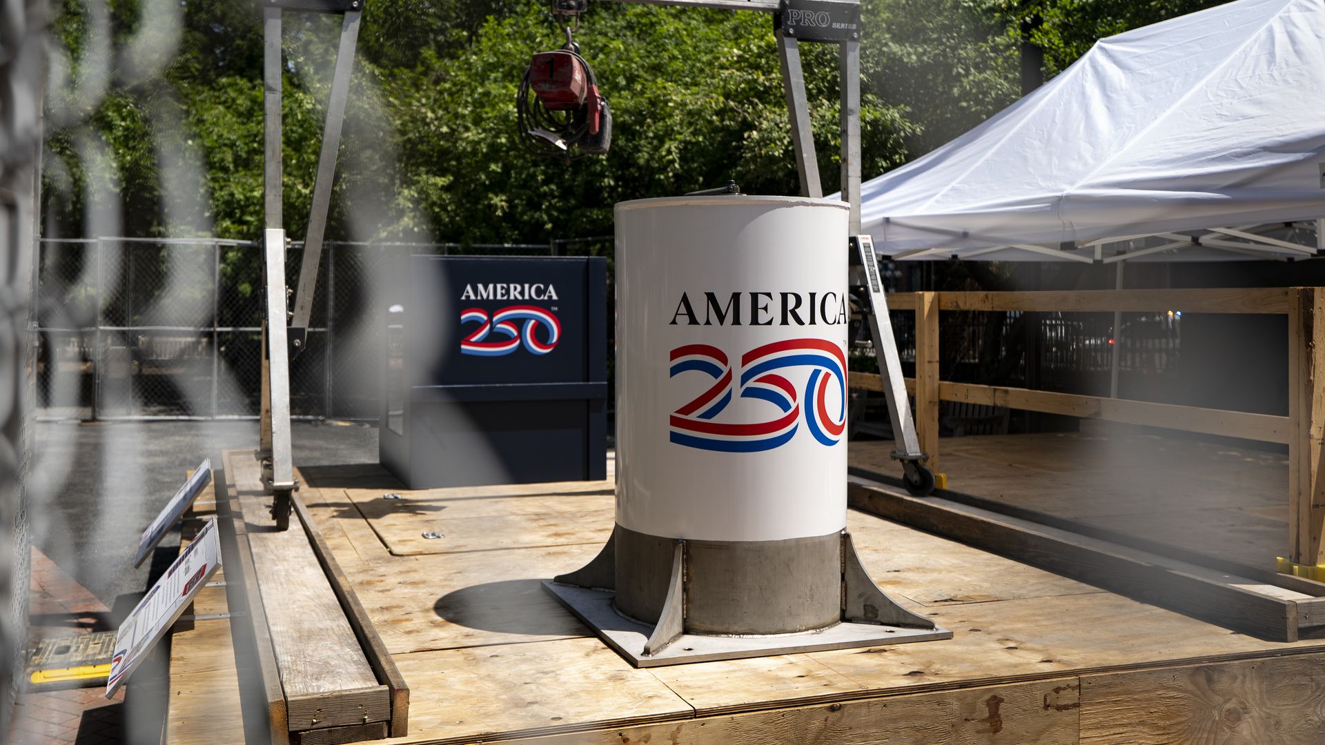 The America 250 time capsule, shaped like a white cylinder, sits on a wooden platform