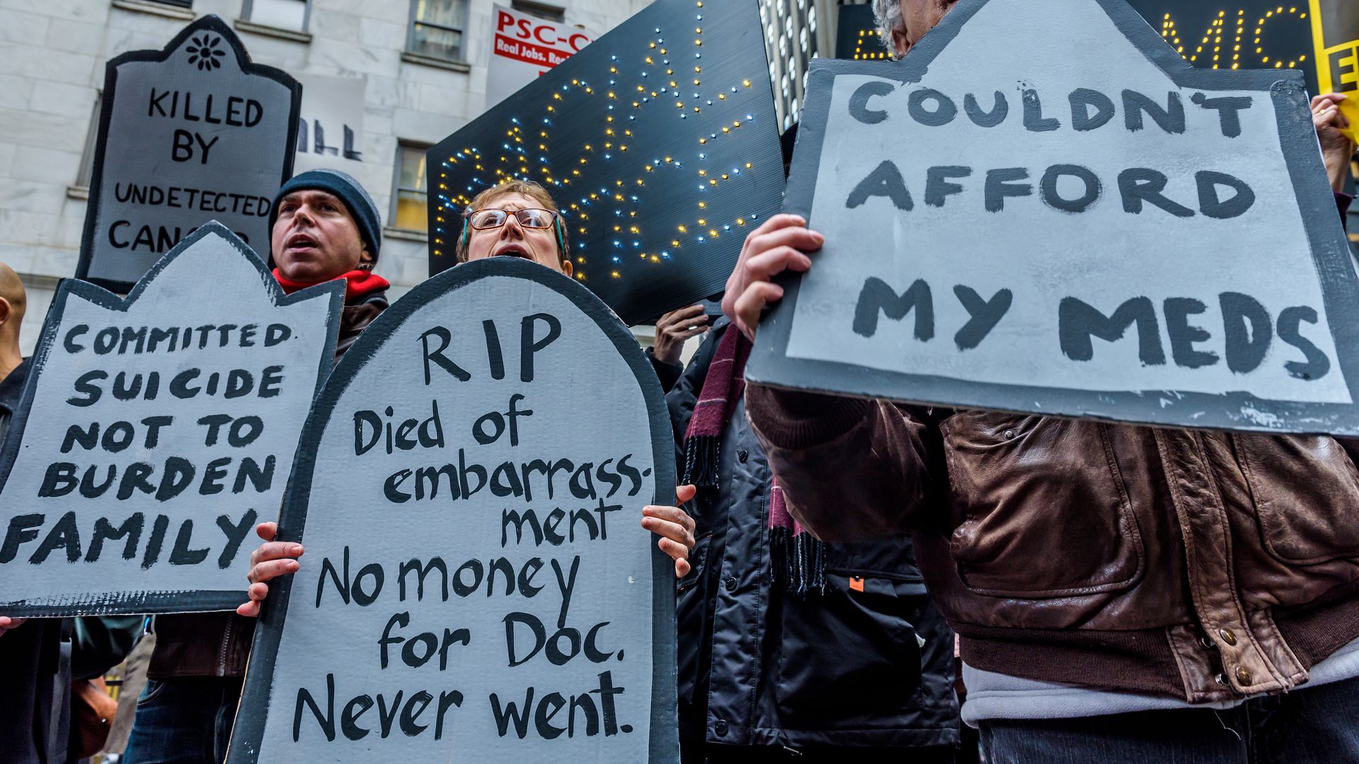 People with gravestones for signs about medicare costs
