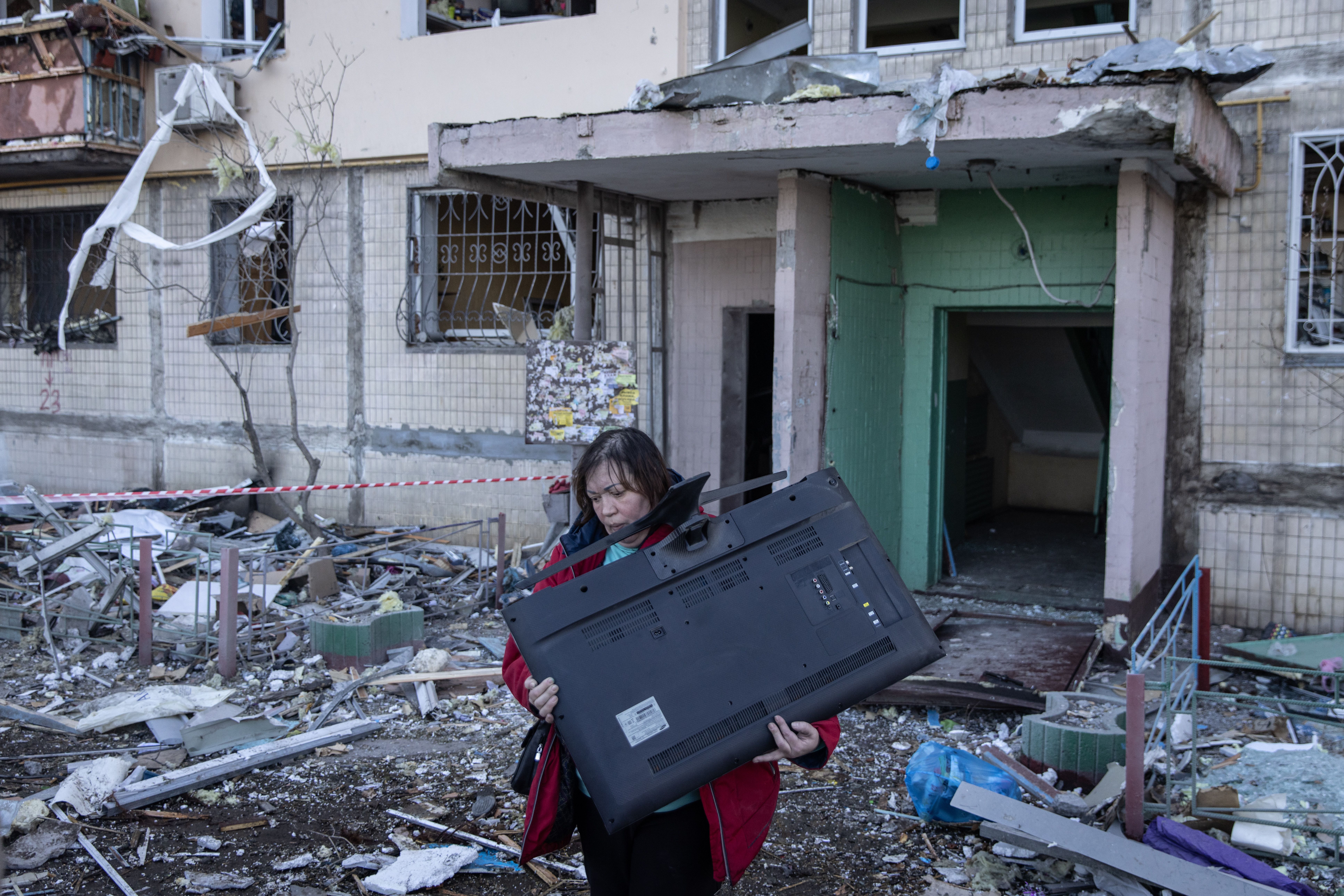 A woman carries a television from a residential apartment block that was hit by Russian shelling on March 14, 2022 in Kyiv, Ukraine. 