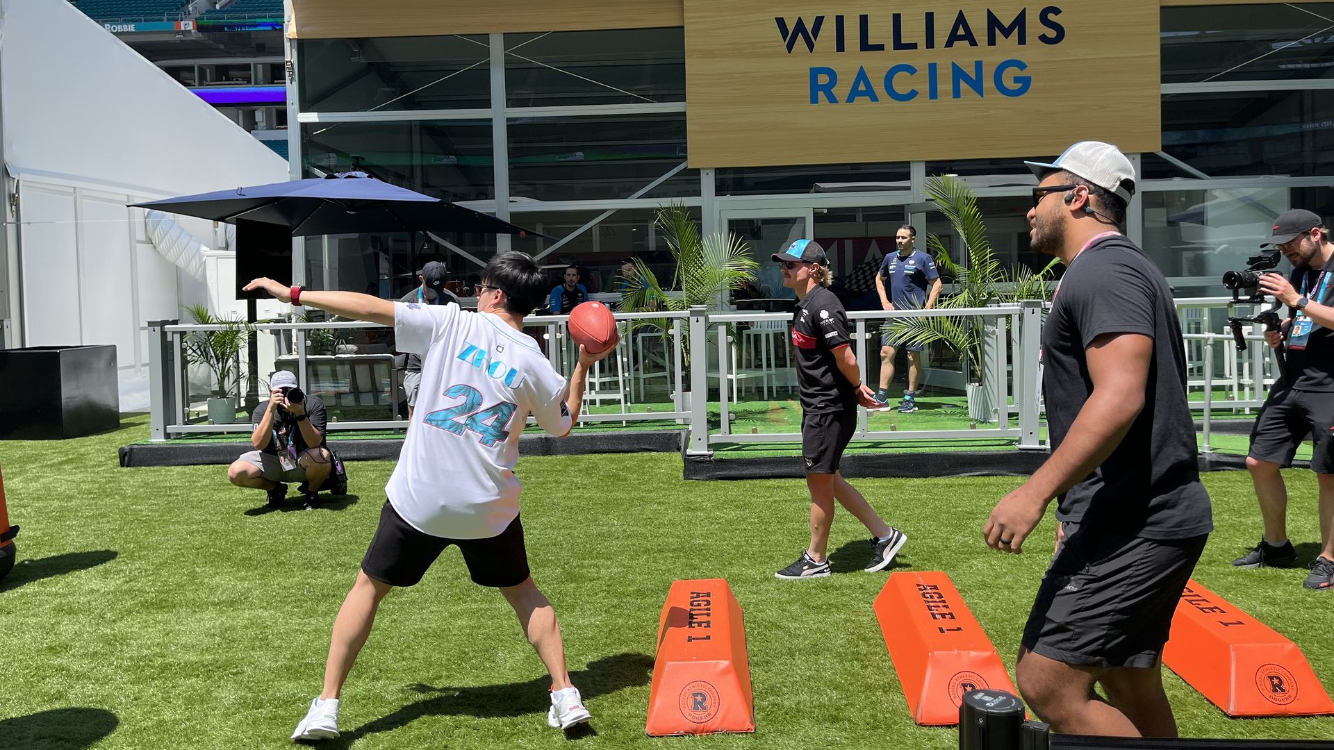 Alfa Romeo driver Zhou Guanyu tosses a football with Dolphins quarterback Tua Tagovailoa.