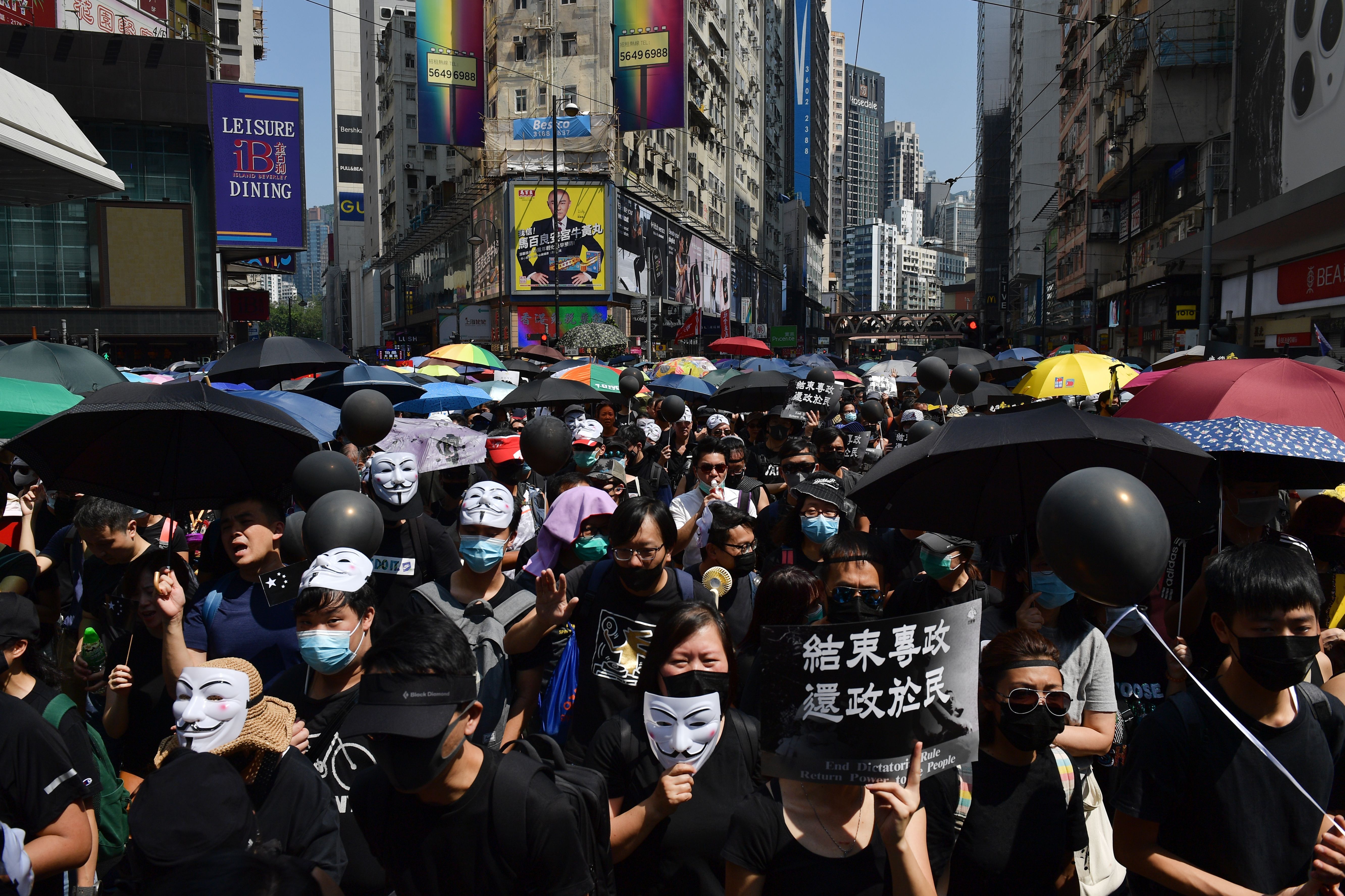 Protesters carry black balloons as they take part in a march in the Causeway Bay shopping district in Hong Kong on October 1