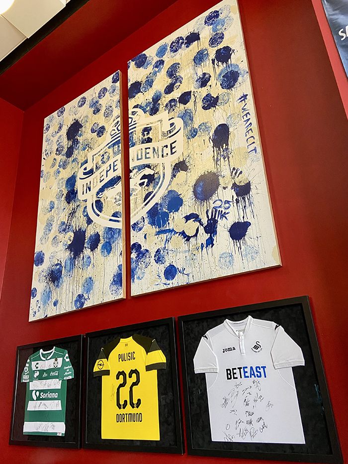 Jerseys hanging on the wall below a mural. 