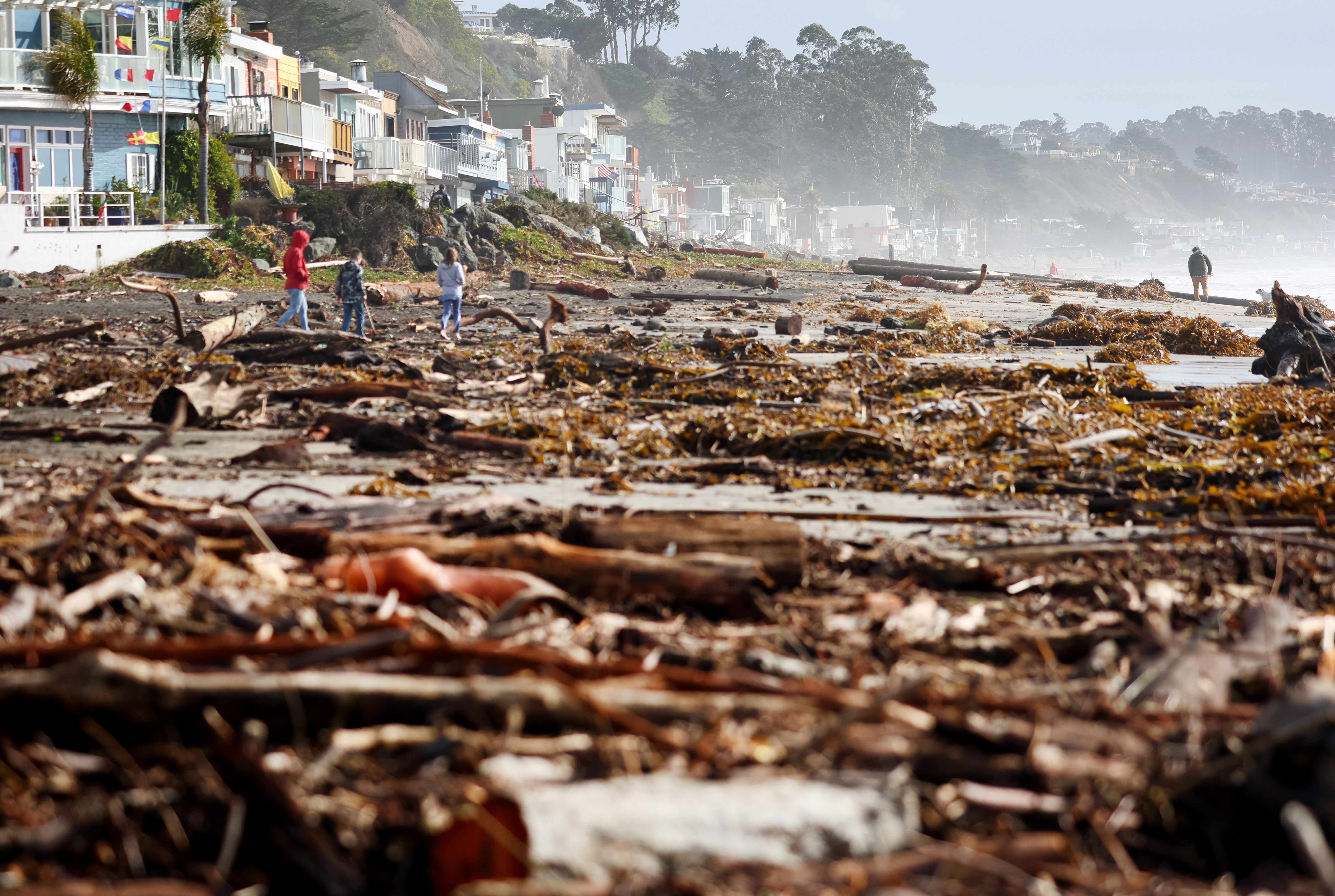 People walk amid storm debris washed up on the beach on January 10, 2022 in Aptos, California. 
