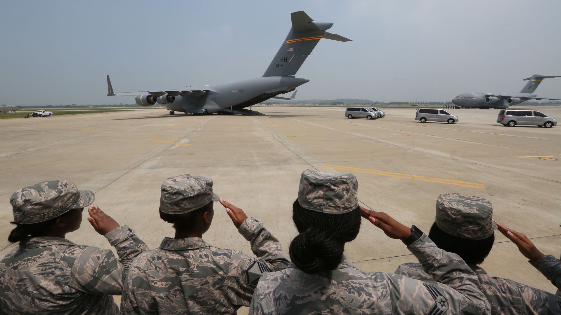 U.S. Soldiers salute vehicles transporting the remains of soldiers killed in the Korean War.