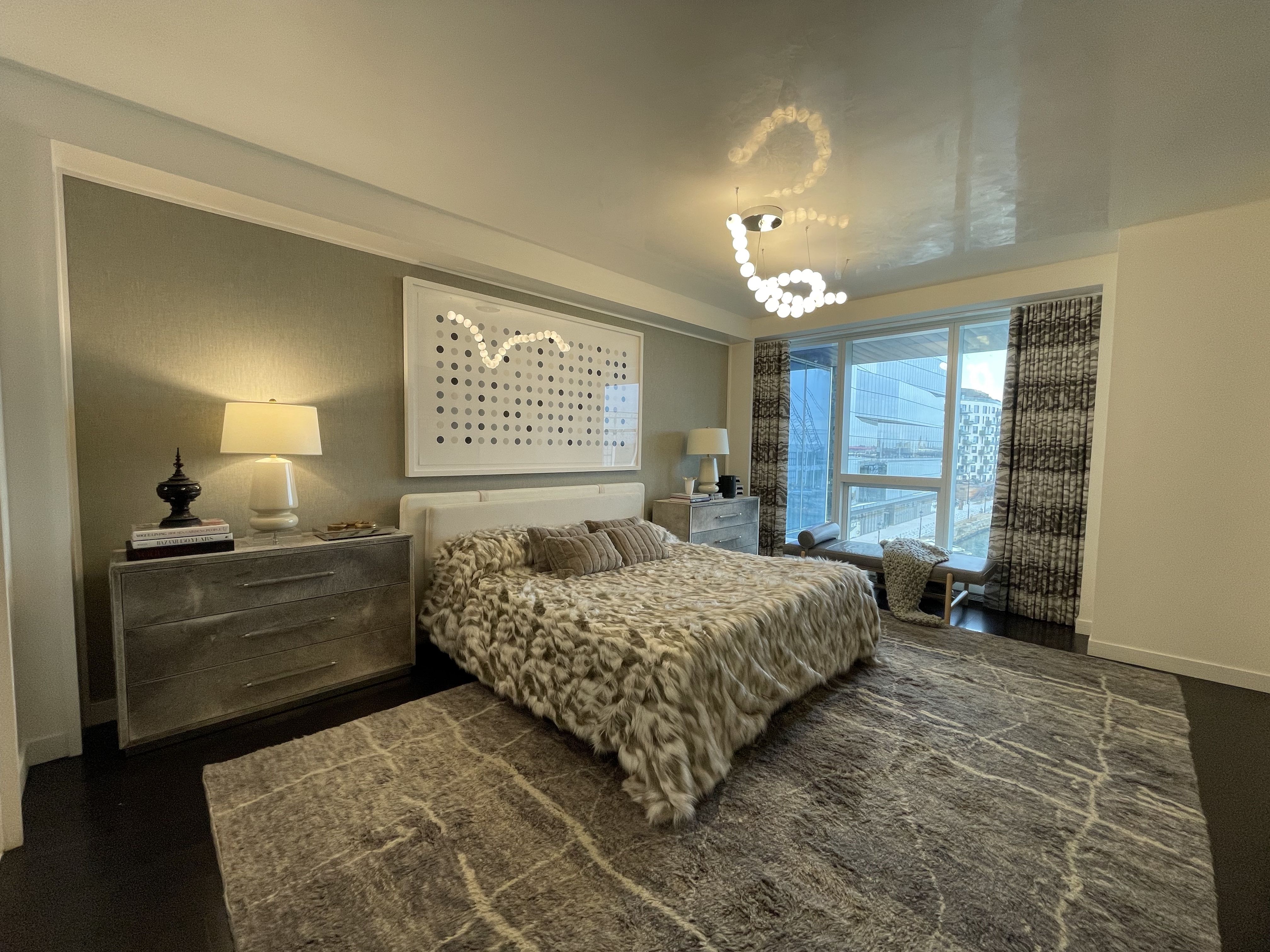 A view of a master bedroom with a queen bed in a St. Regis condos, including floor-to-ceiling windows with waterfront views.