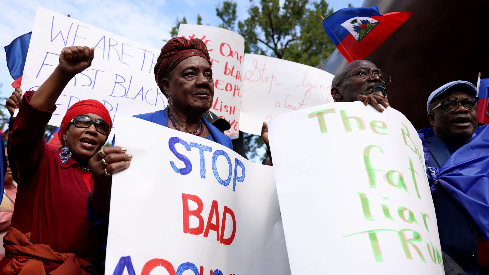 A group of Haitian immigrants unite in protest with one sign that reads "Stop Bad Accusations" 