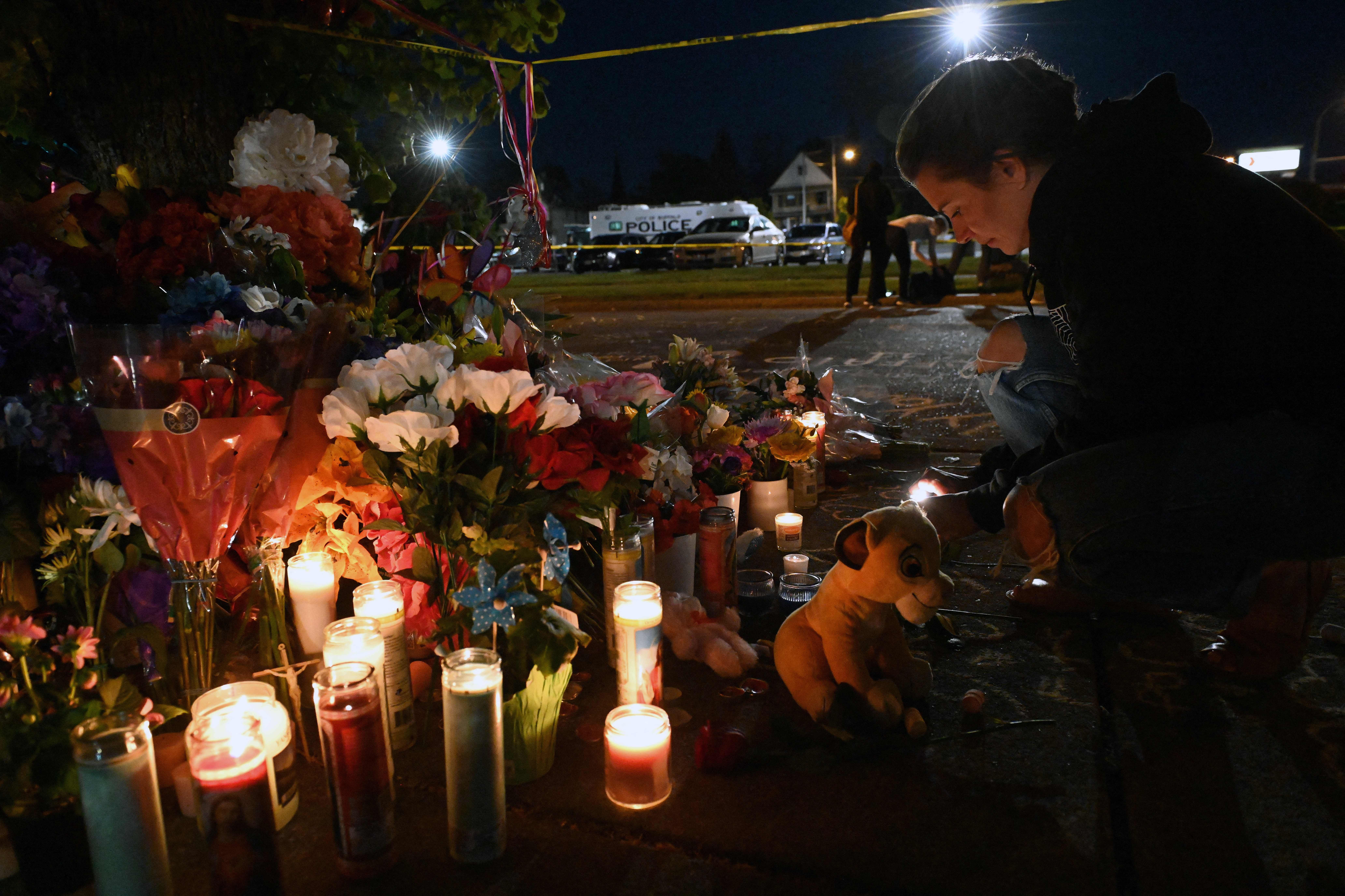 People light candles at a makeshift memorial 